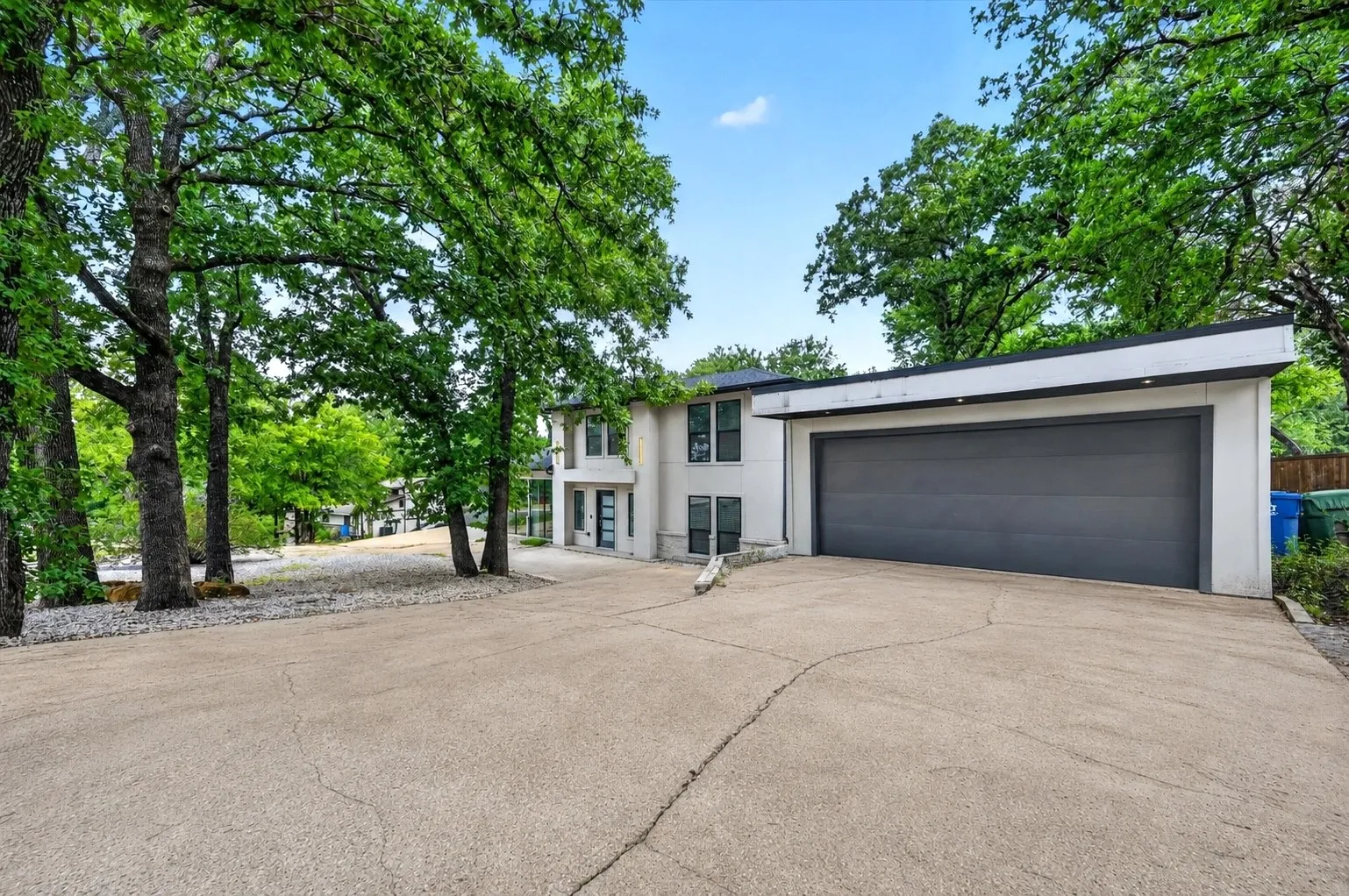Two-story contemporary residence featuring a dark gray garage door and a concrete driveway
