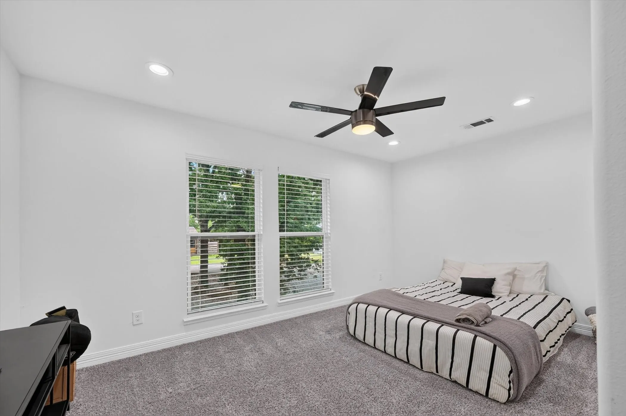 Carpeted room featuring two windows with blinds, recessed lighting, and a ceiling fan with light fixture