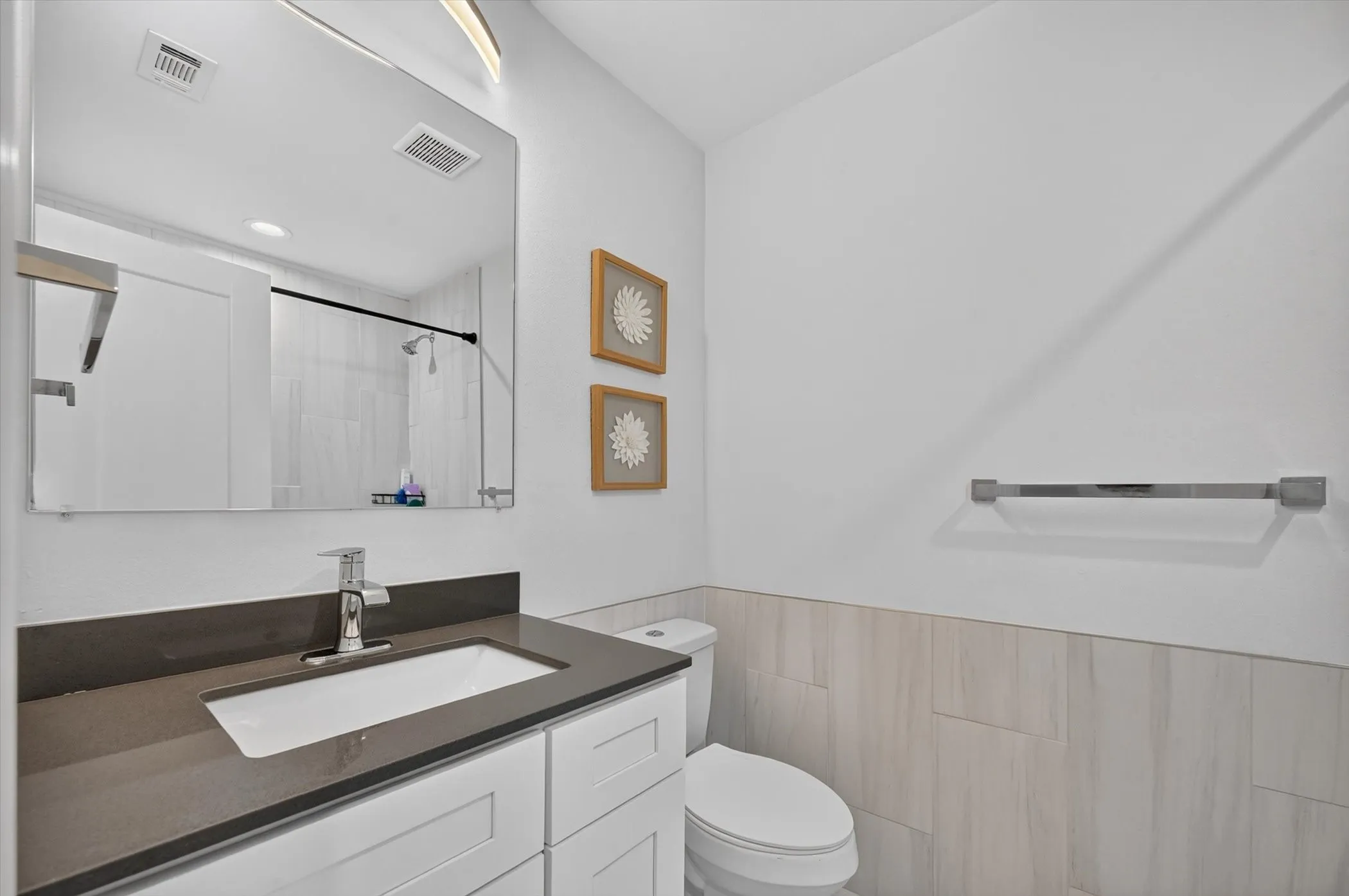 Contemporary vanity featuring a rectangular undermount sink, dark countertop, and chrome faucet