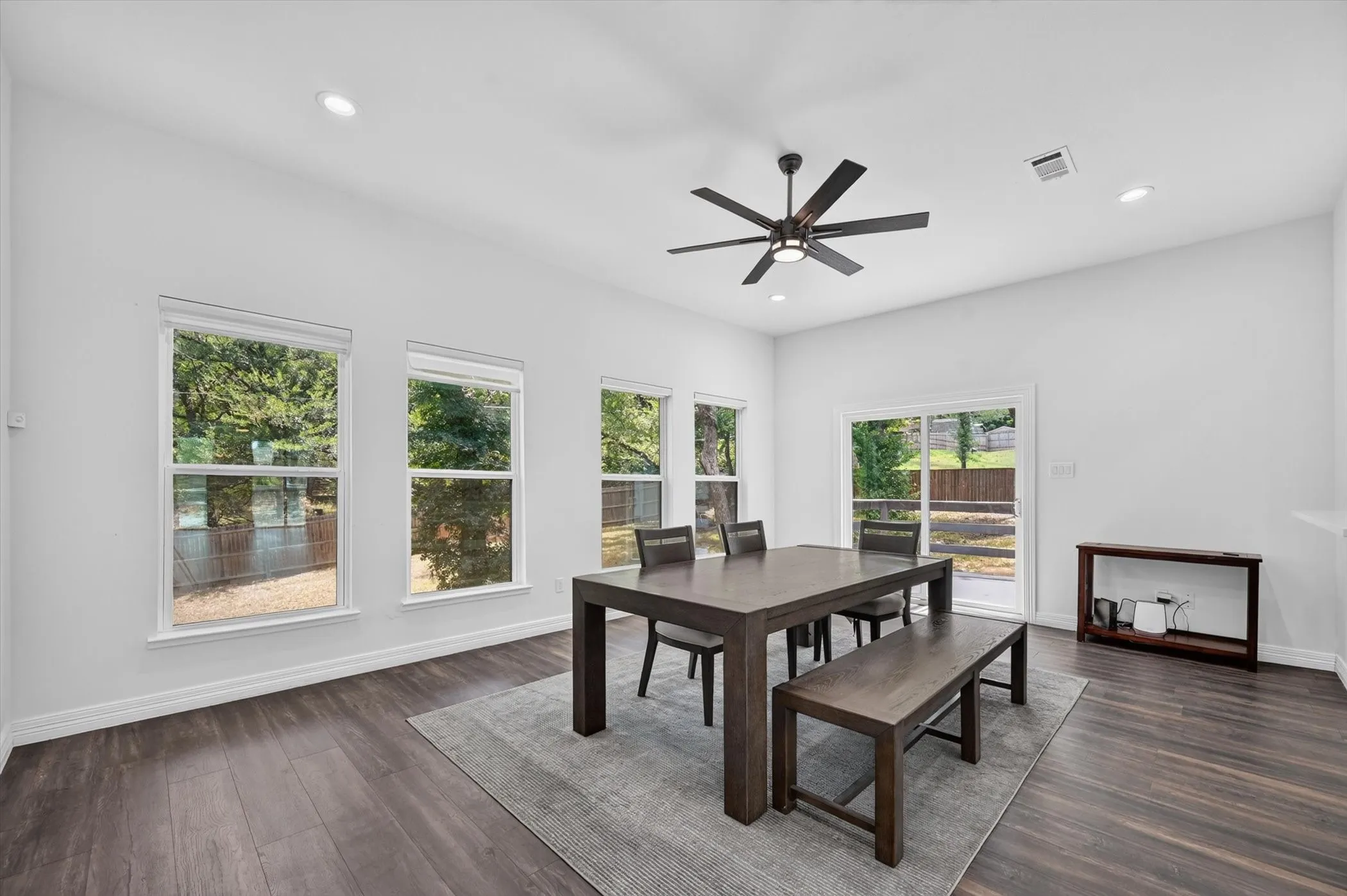 Spacious dining area featuring wood-finish flooring, recessed lighting, and a contemporary ceiling fan