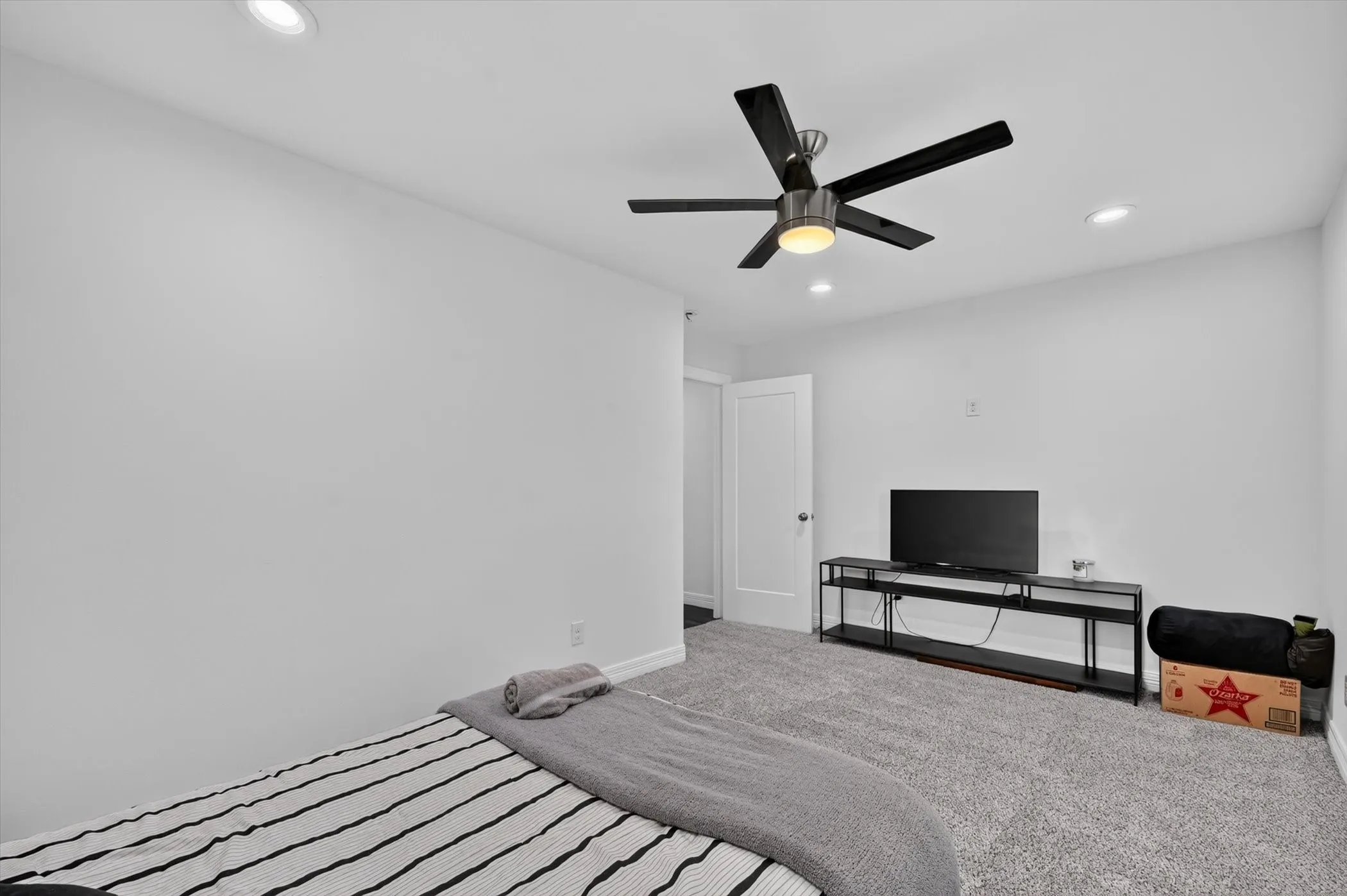 Carpeted room featuring a ceiling fan with integrated lighting, recessed lighting, and a white interior door
