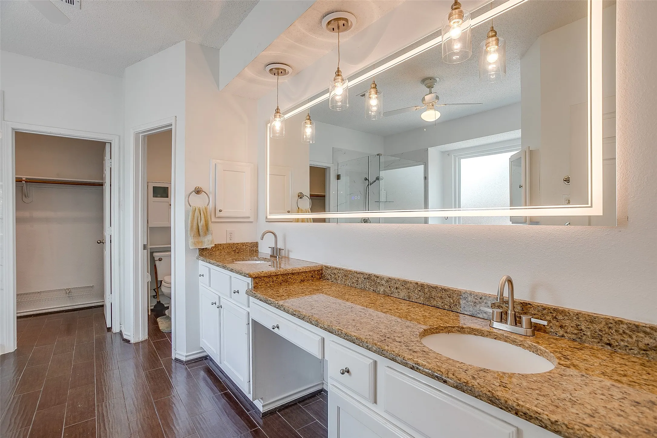LED backlit mirror with pendant lighting.