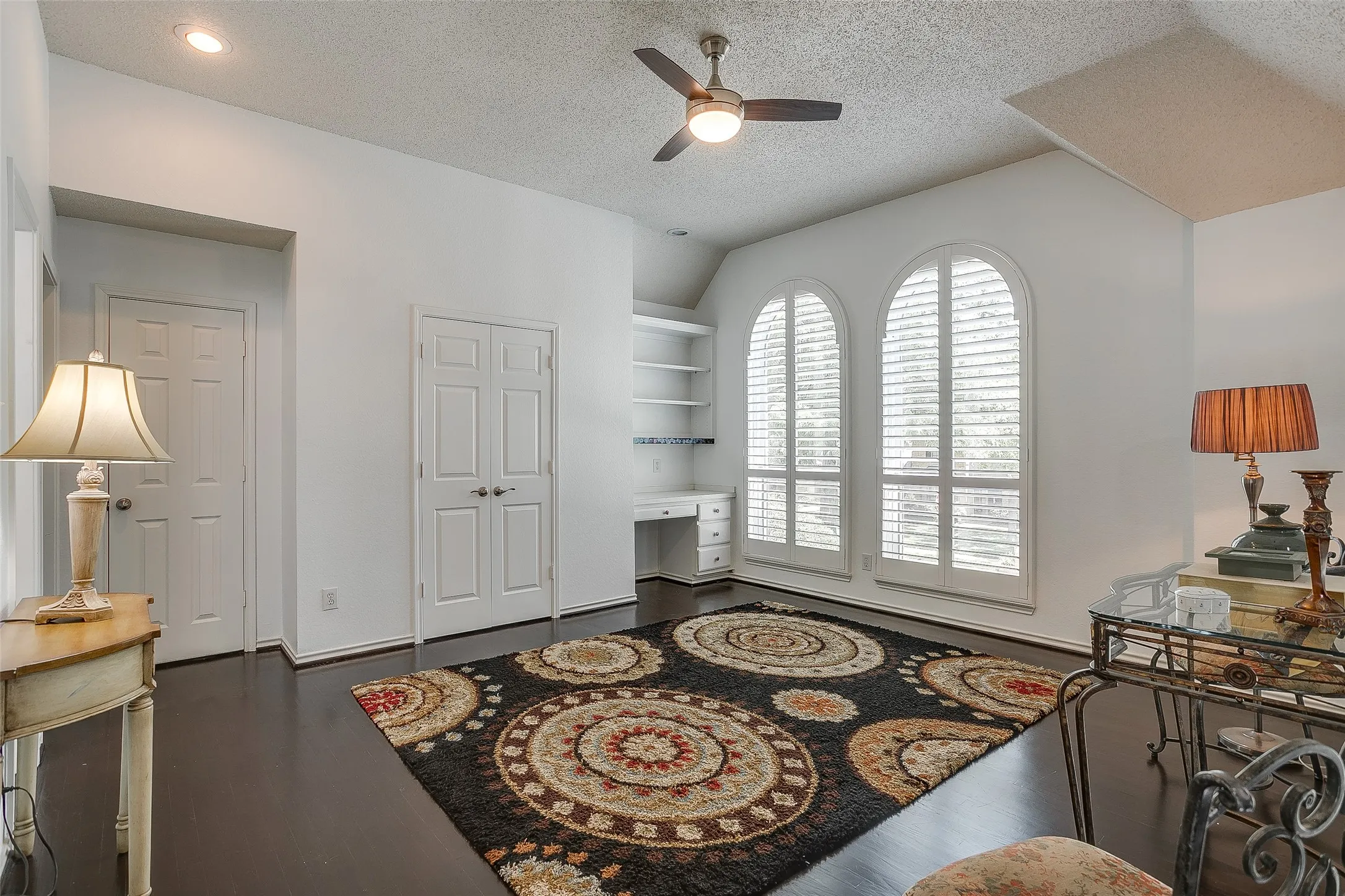 Third living room with built in shelving, rich wood floors, and beautiful windows.
