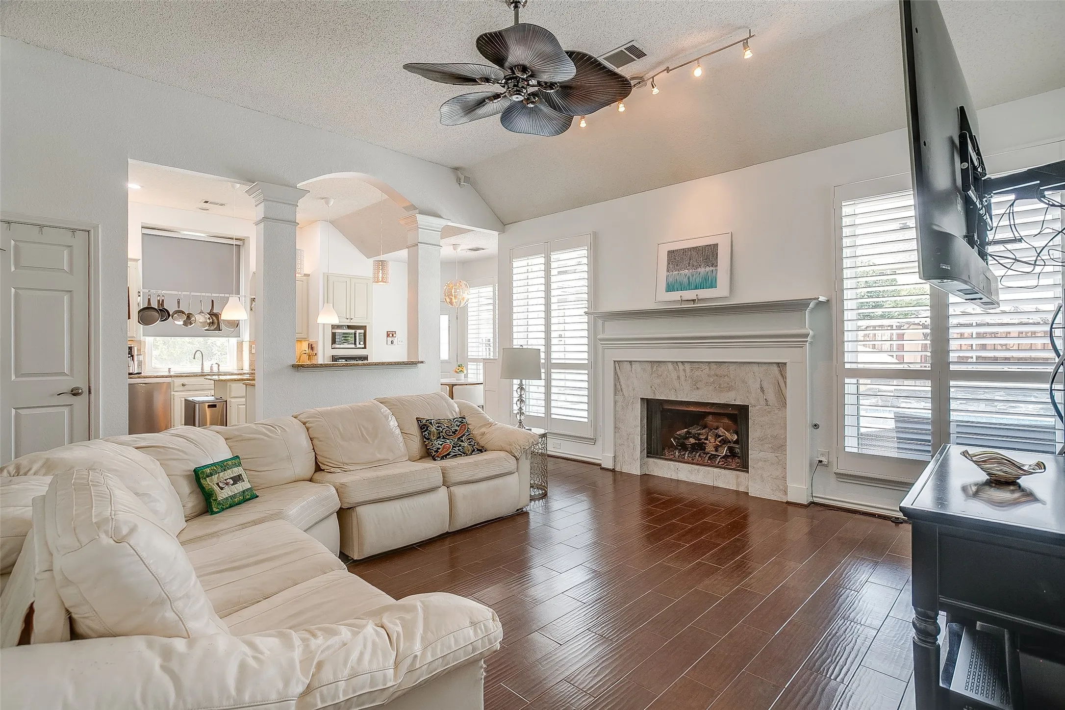 Spacious living room number two; featuring a fireplace centered between large windows covered with custom shutters.