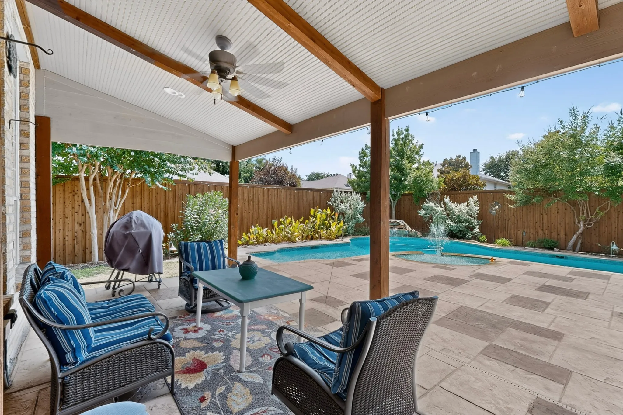 COVERED BACK PATIO WITH VIEW OF POOL AND WATERFALL FEATURE