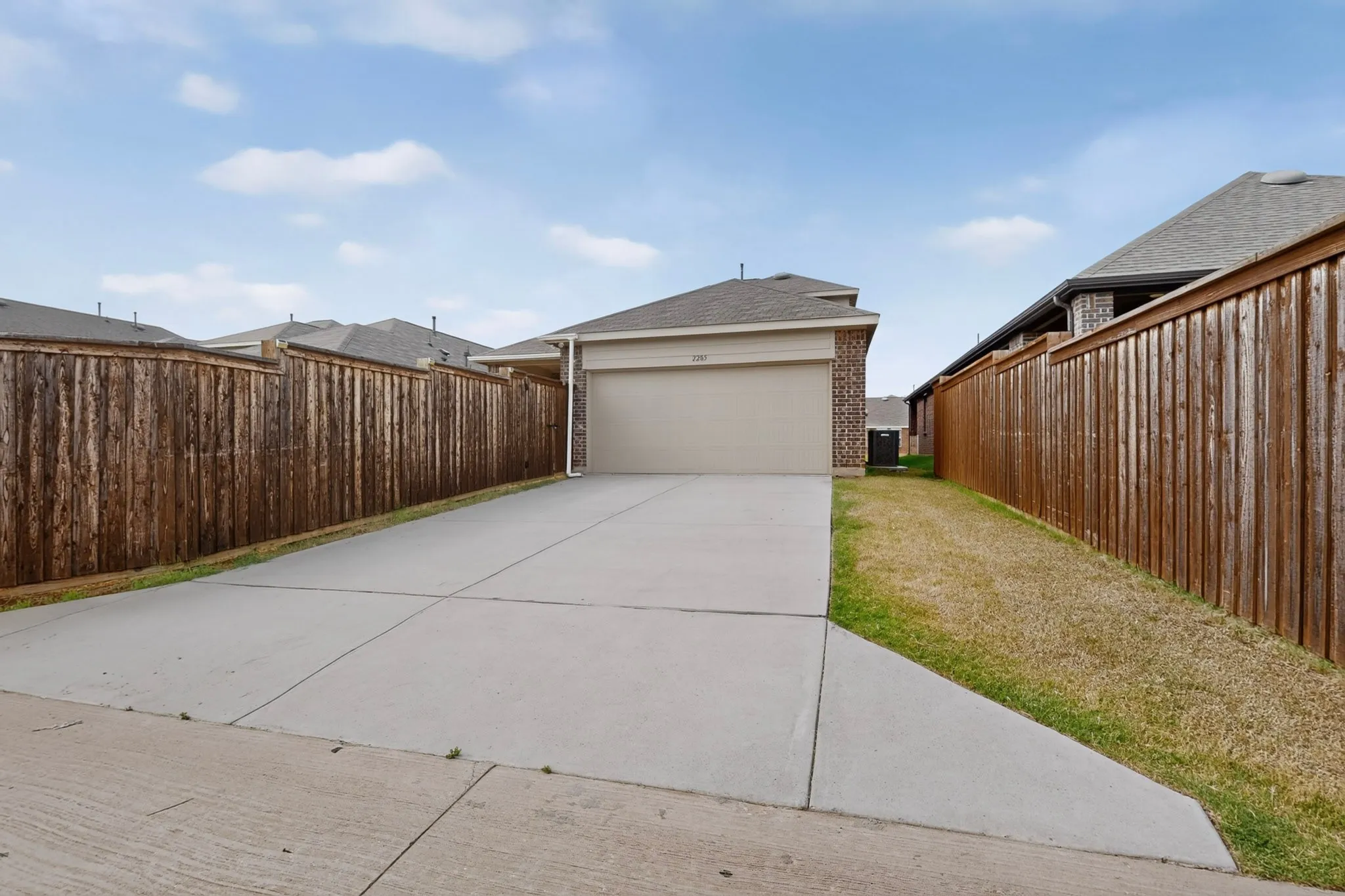 Exterior featuring a two-car garage, brick facade, and a concrete driveway