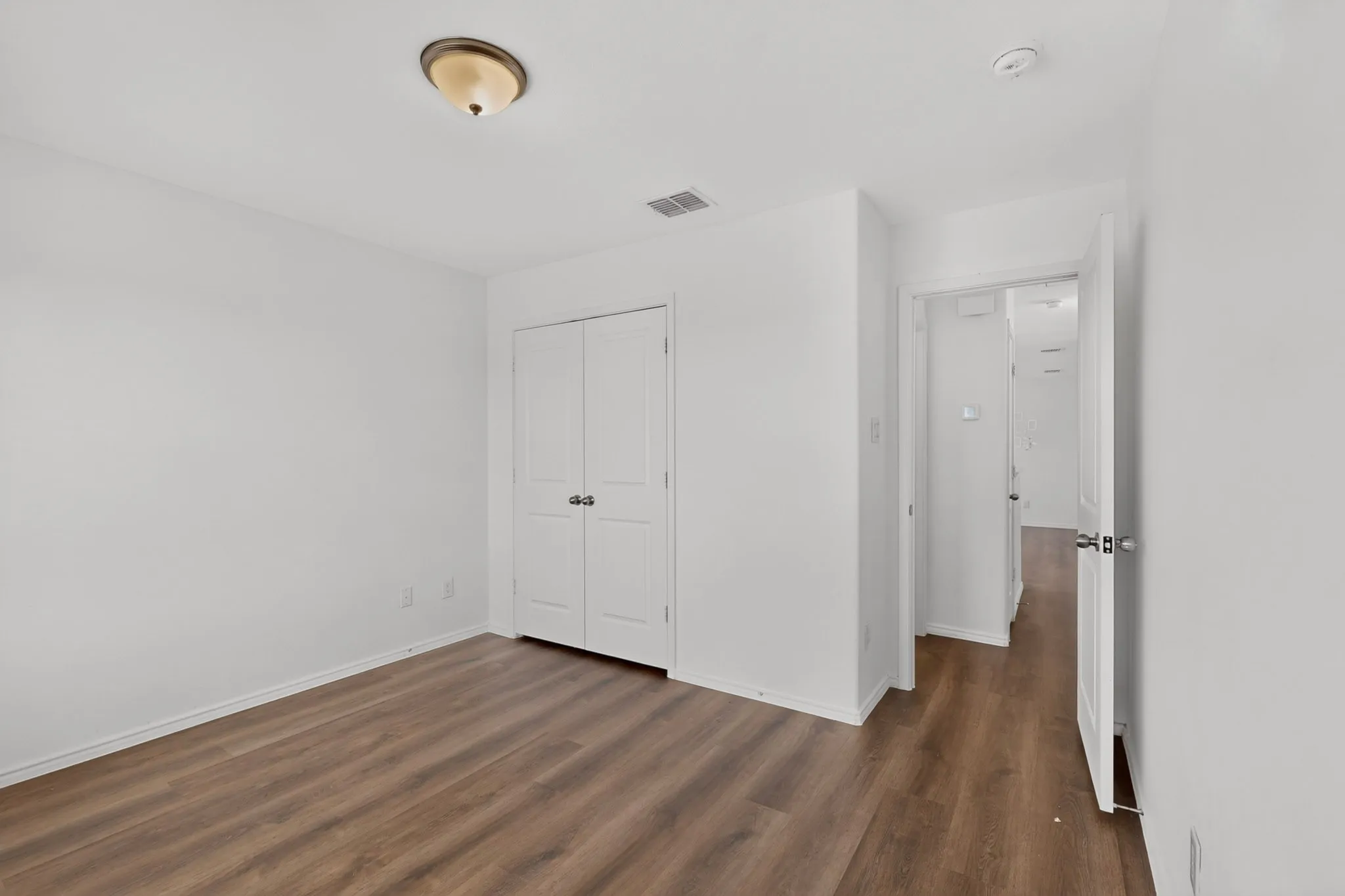 Interior room featuring wood-finish flooring and white baseboards