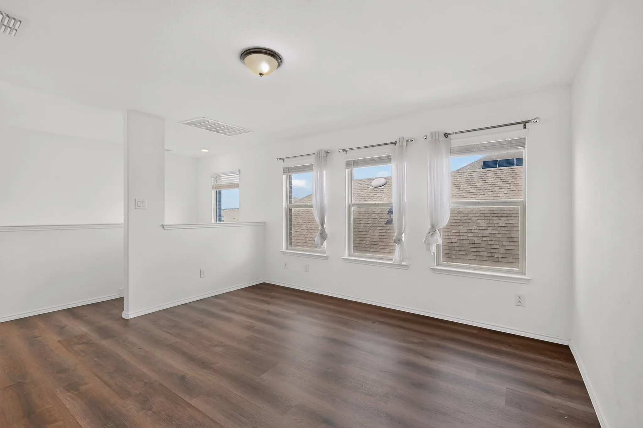 Spacious loft area featuring wood-finish flooring, recessed lighting, and a semi-partition wall