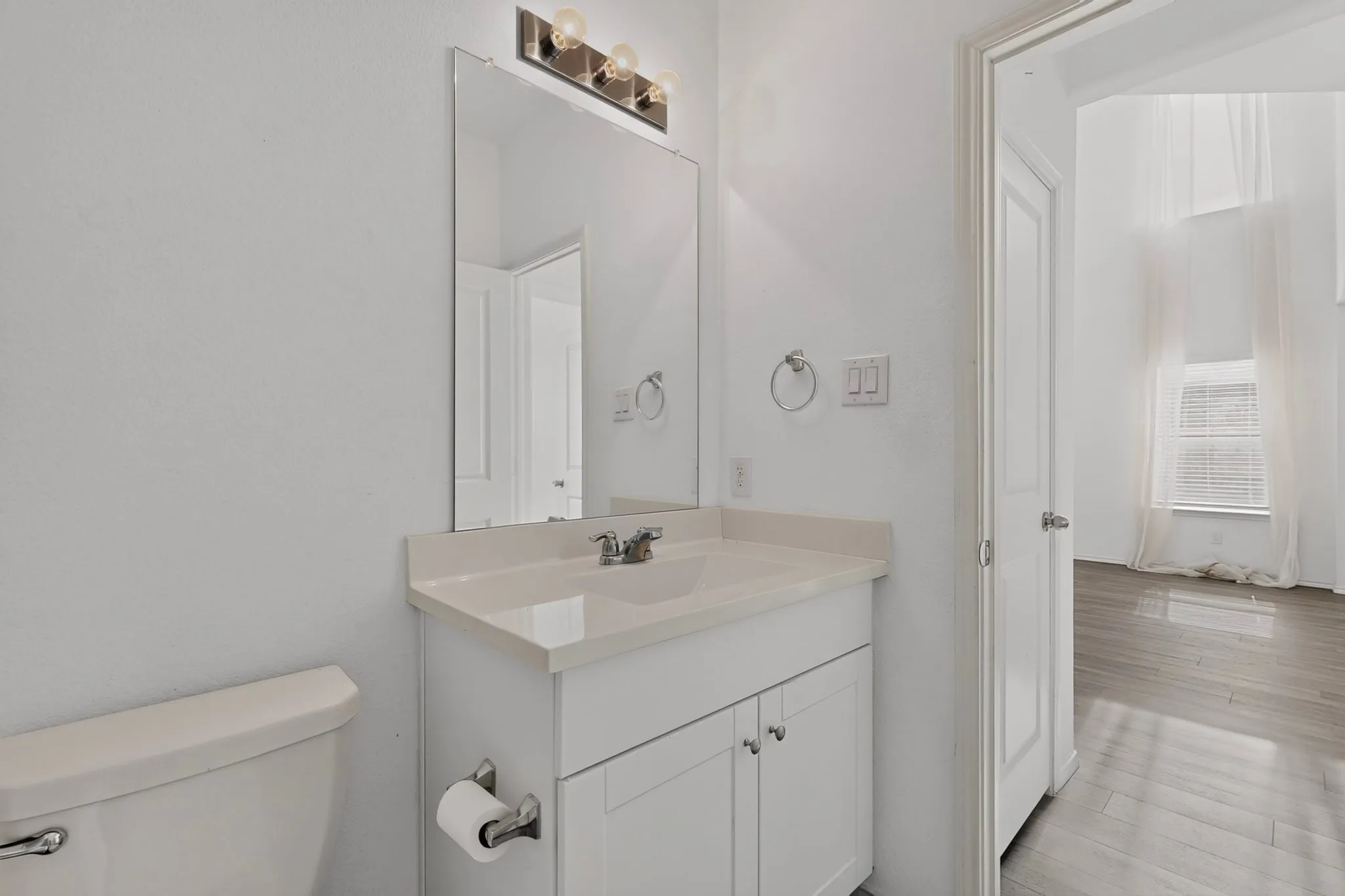 Bathroom vanity featuring a light-toned countertop, integrated sink, and white cabinetry