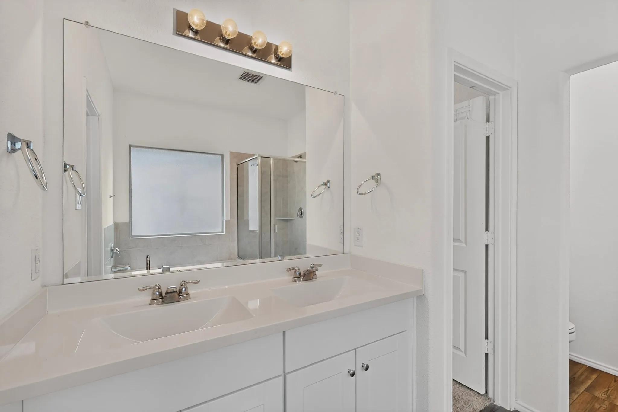 Double vanity featuring white cabinetry, integrated sinks, and polished chrome faucets
