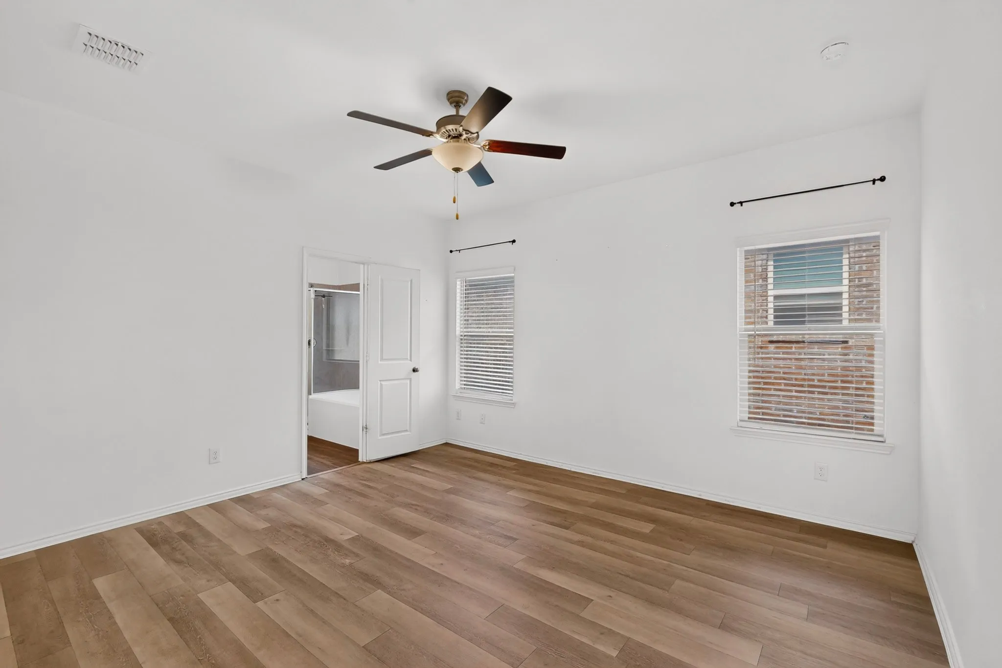 Spacious room featuring wood-finish flooring and a ceiling fan
