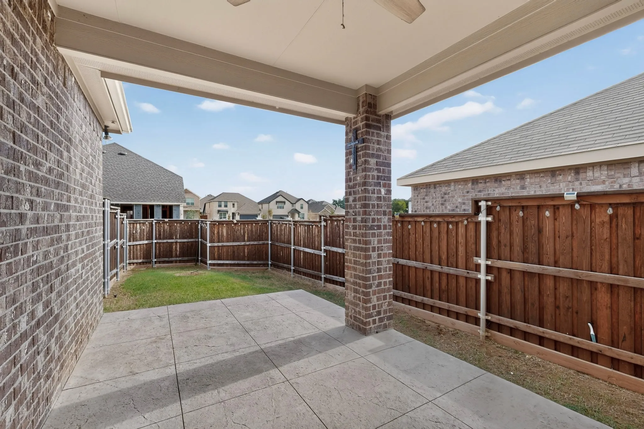 Covered patio featuring a ceiling fan and brick pillar