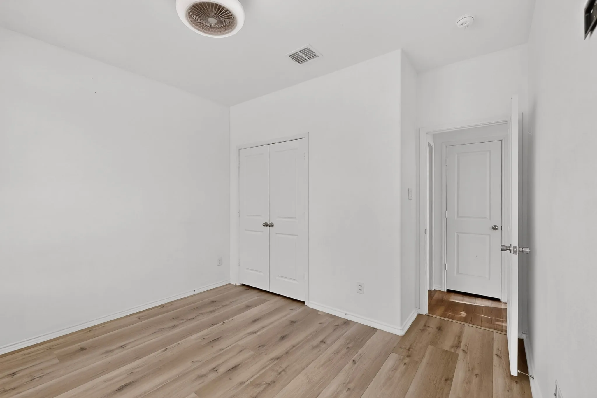 Room featuring wood-finish flooring, white walls, and a ceiling-mounted light fixture
