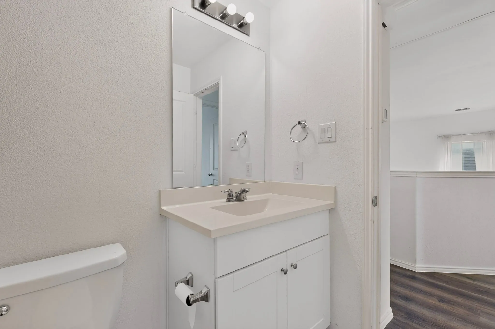 Bathroom vanity featuring a light-toned countertop, undermount sink, and chrome faucet
