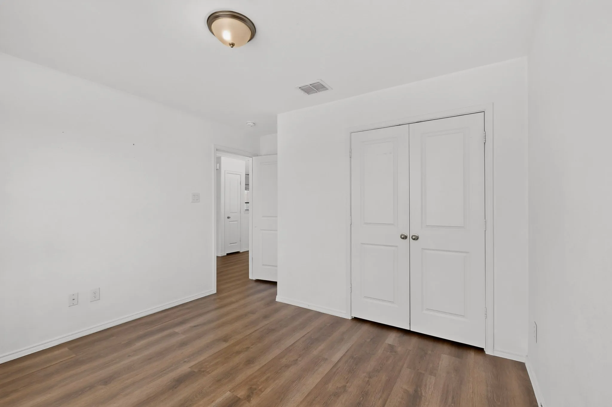 Room featuring wood-finish flooring, white walls, and bright white baseboards
