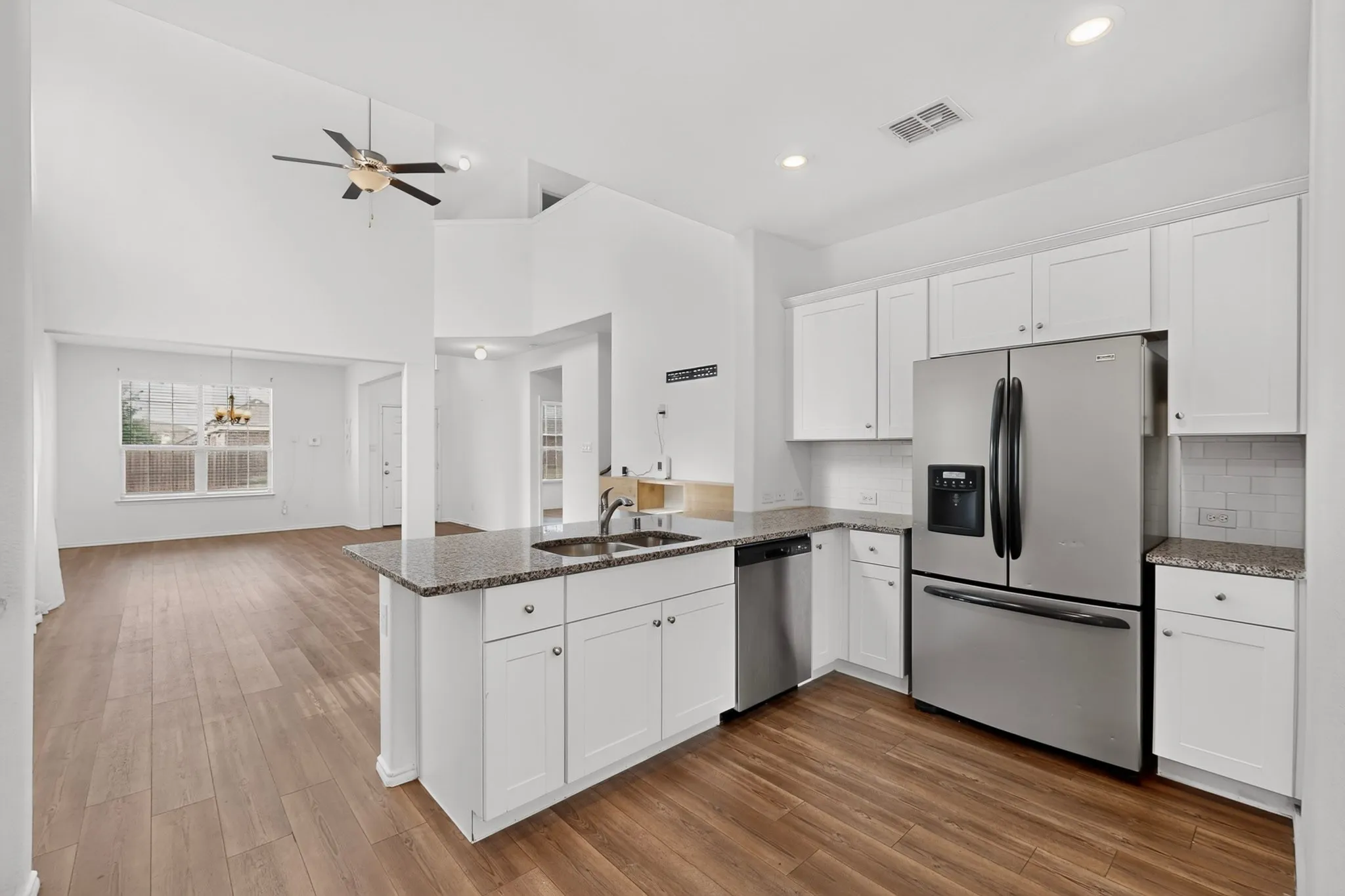 Kitchen featuring white cabinetry, stainless steel appliances, granite countertops, and a subway tile backsplash