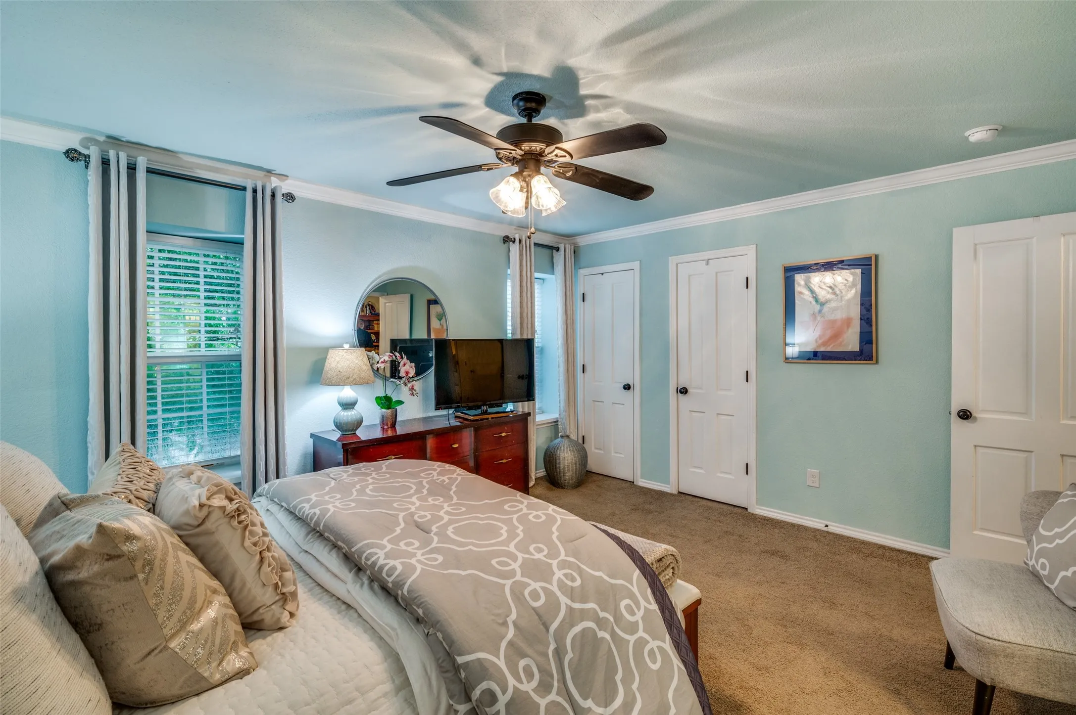 Bedroom with ornamental molding, multiple closets, ceiling fan, and carpet