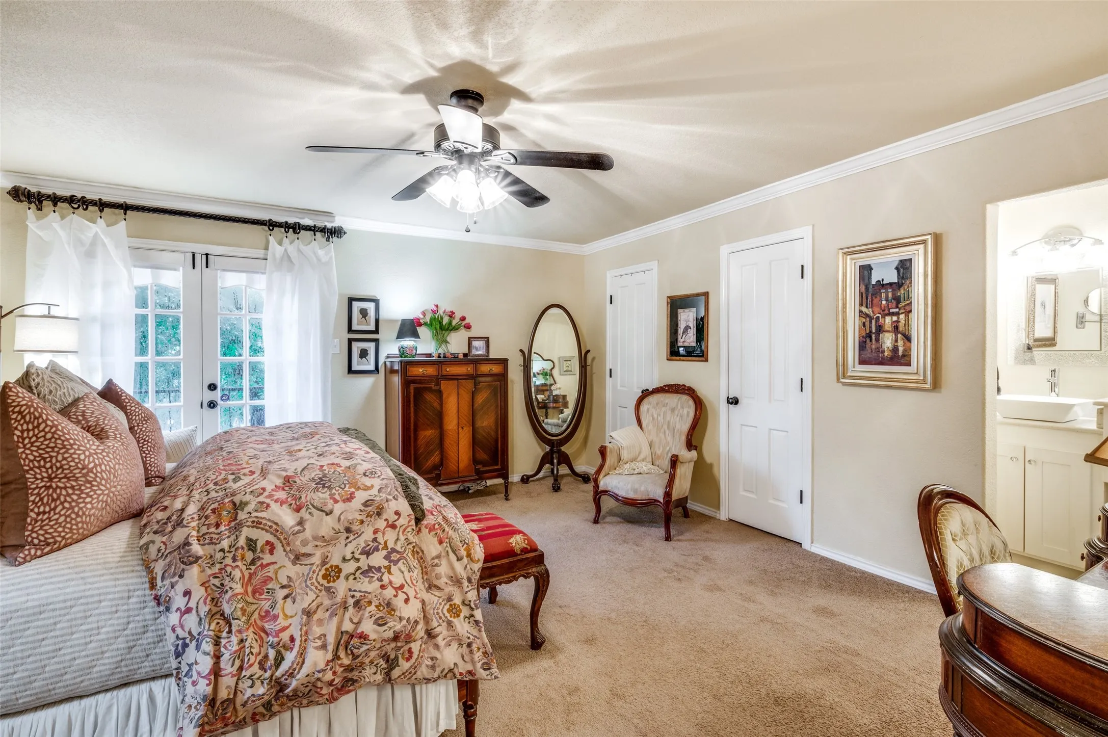 Carpeted bedroom featuring ensuite bathroom, french doors, ornamental molding, sink, and ceiling fan