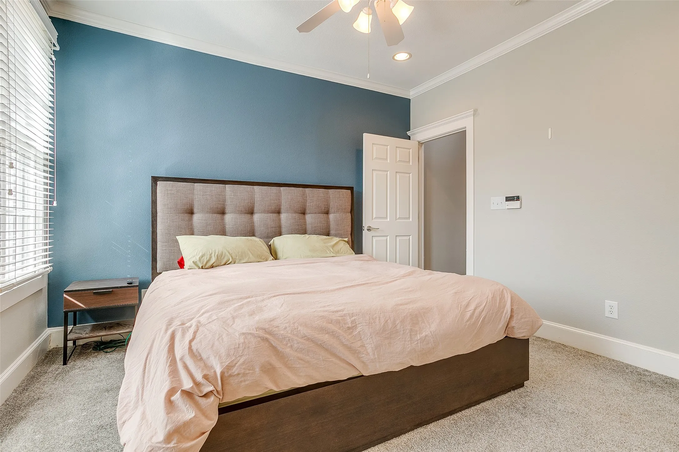 Bedroom featuring light gray carpeting, a window with horizontal blinds, a ceiling fan with integrated lighting, recessed lighting, and crown molding