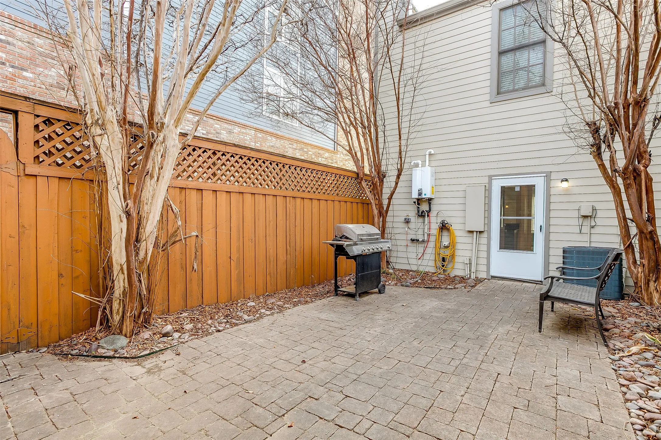 Paved patio area featuring brick-patterned pavers and a wood privacy fence with lattice detailing
