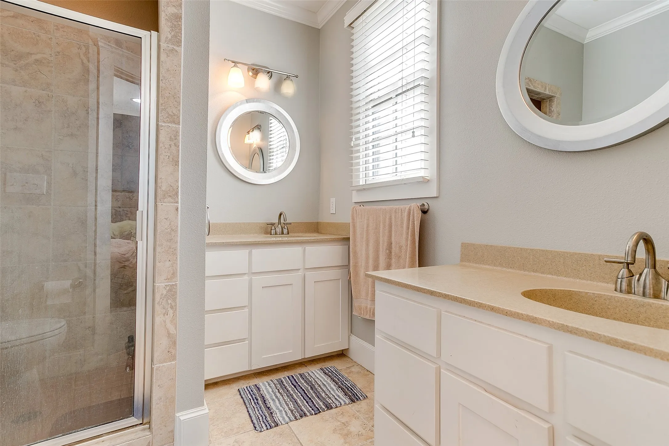 Dual vanity with light-colored countertops and white cabinetry