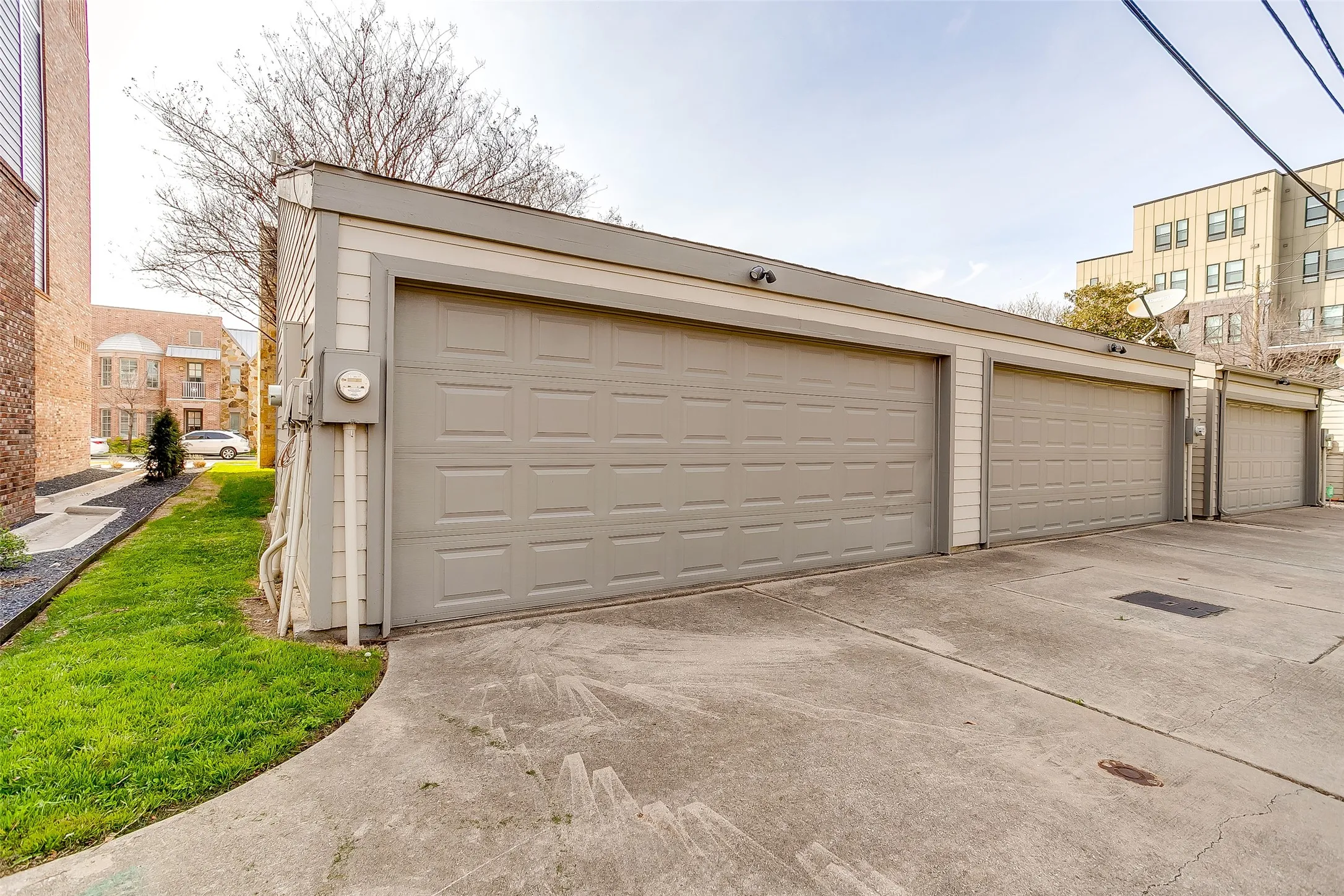 Detached three-car garage featuring panel-style doors and exterior sconce lighting