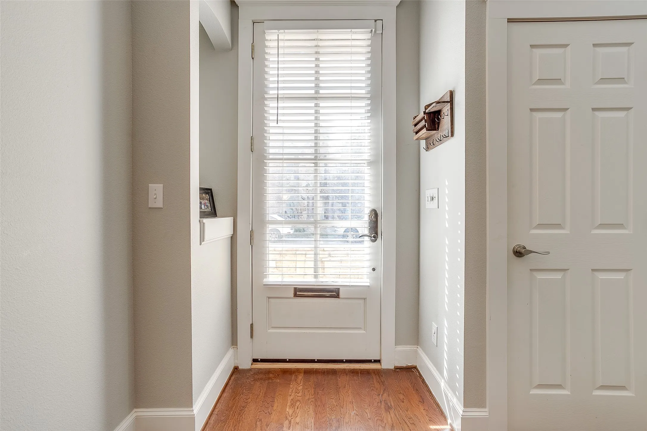 Entryway featuring wood-finish flooring, a white paneled door, and a built-in wall niche with shelving
