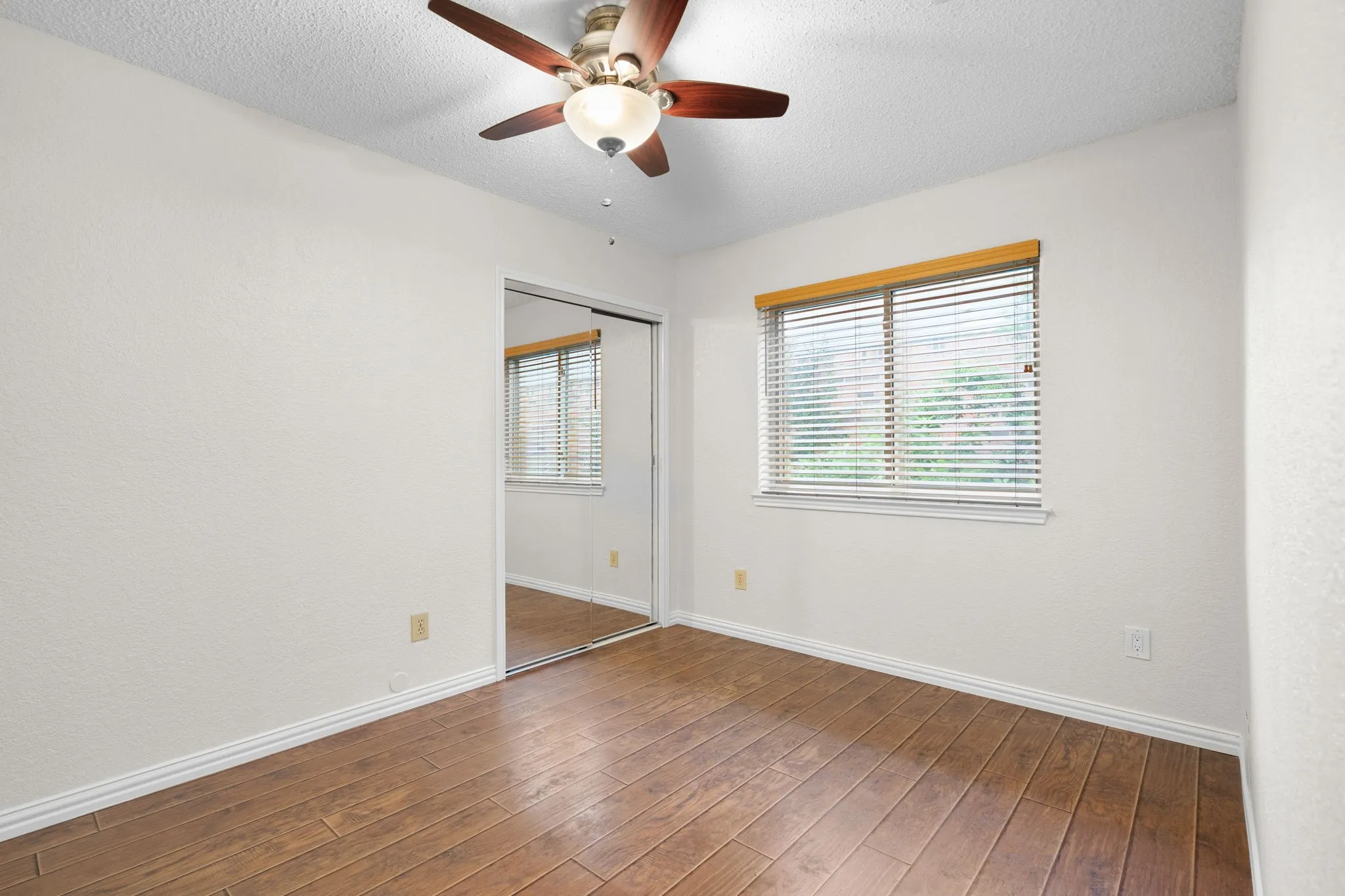 This secondary bedroom has a ceiling fan and is split from the primary bedroom.
