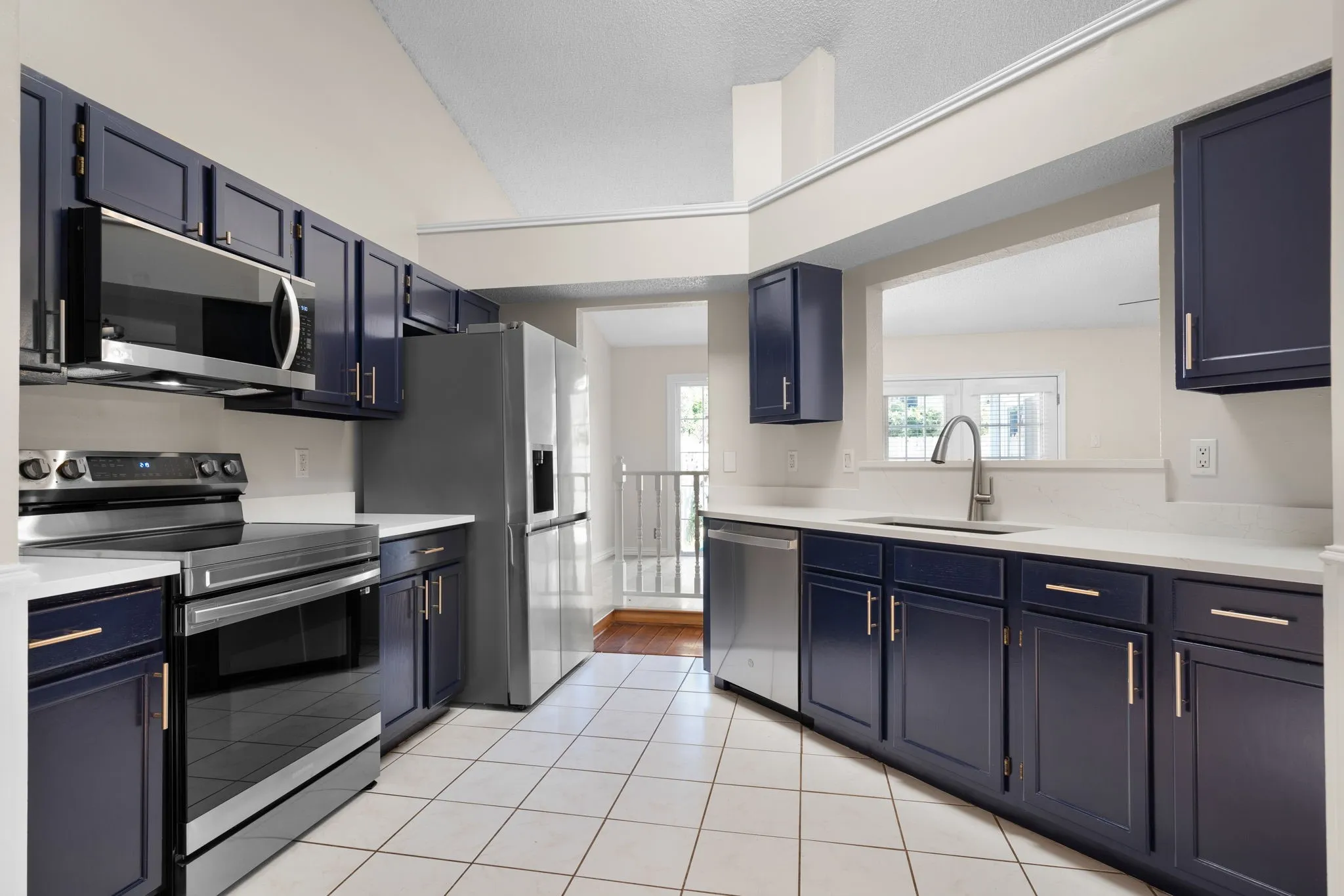 The updated kitchen has stainless appliances, quartz counters and navy storage cabinets.