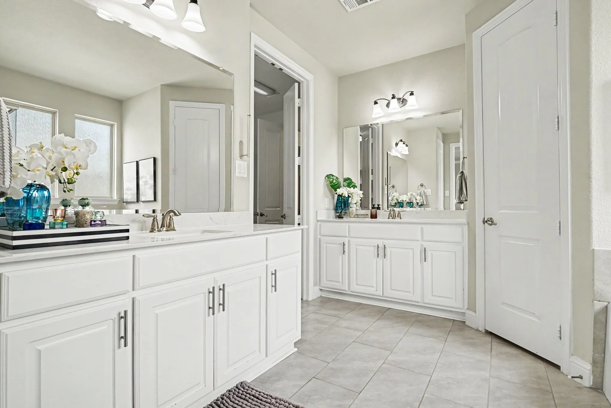 1st Floor Primary Bathroom featuring dual vanity countertops, white cabinetry and brushed nickel hardware