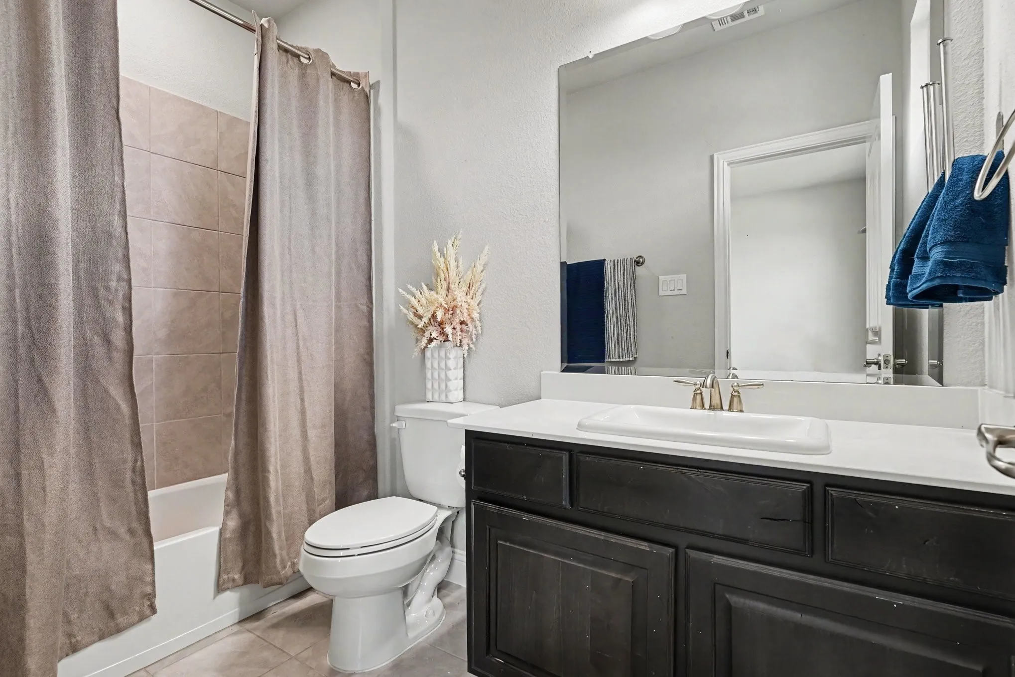 Front 2nd Floor EnSuite Bathroom featuring a dark wood-finish vanity with a light-colored countertop, an undermount sink, a large wall-mounted mirror, and a bathtub with tiled surround