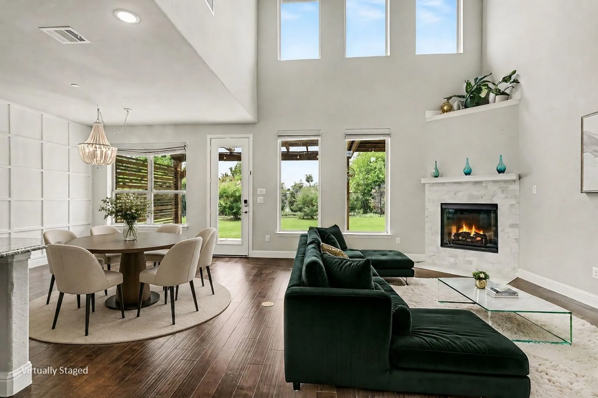 Virtually Staged Living Area featuring high ceilings, dark wood-finish flooring, and a corner fireplace with a light-colored tile surround