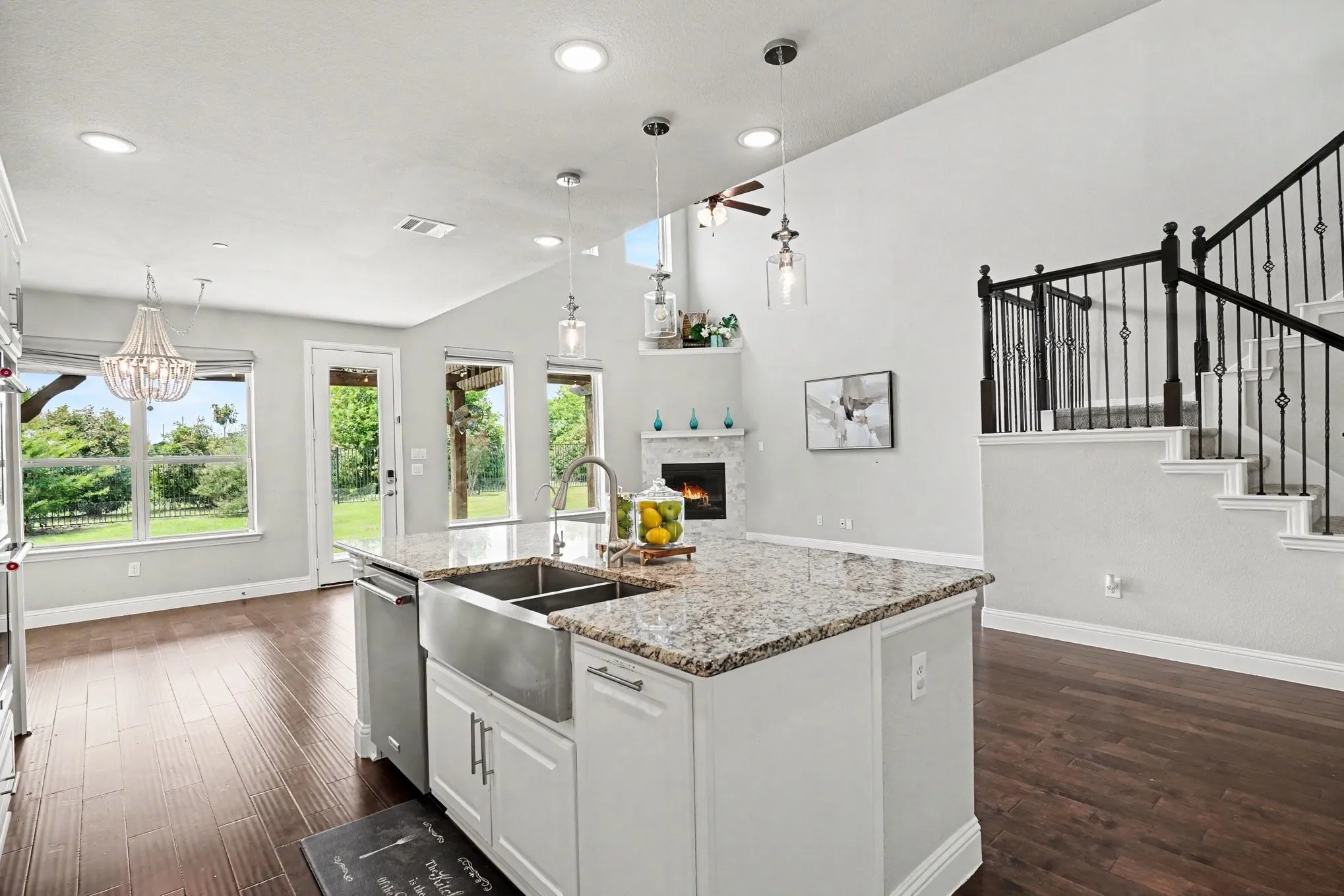 Open-concept kitchen featuring an island with a farmhouse sink, granite countertops, and white cabinetry