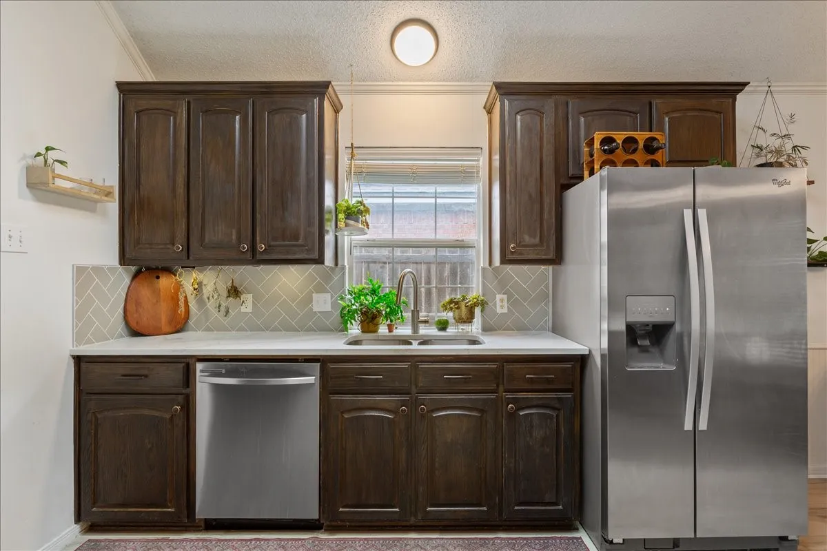 Kitchen featuring dark wood cabinetry, light countertops, and a herringbone-patterned tile backsplash