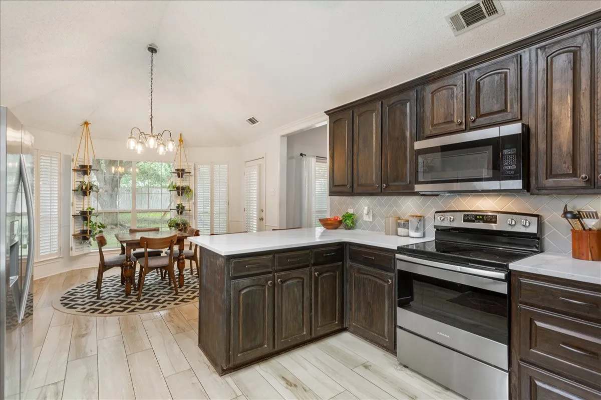 Kitchen featuring dark wood cabinetry, light countertops, and stainless steel appliances