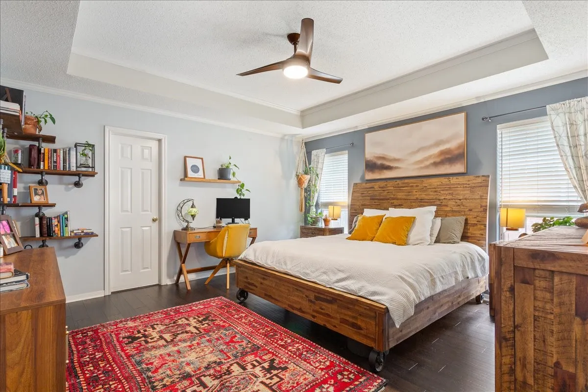 Bedroom featuring dark wood-finish flooring and a tray ceiling with a ceiling fan