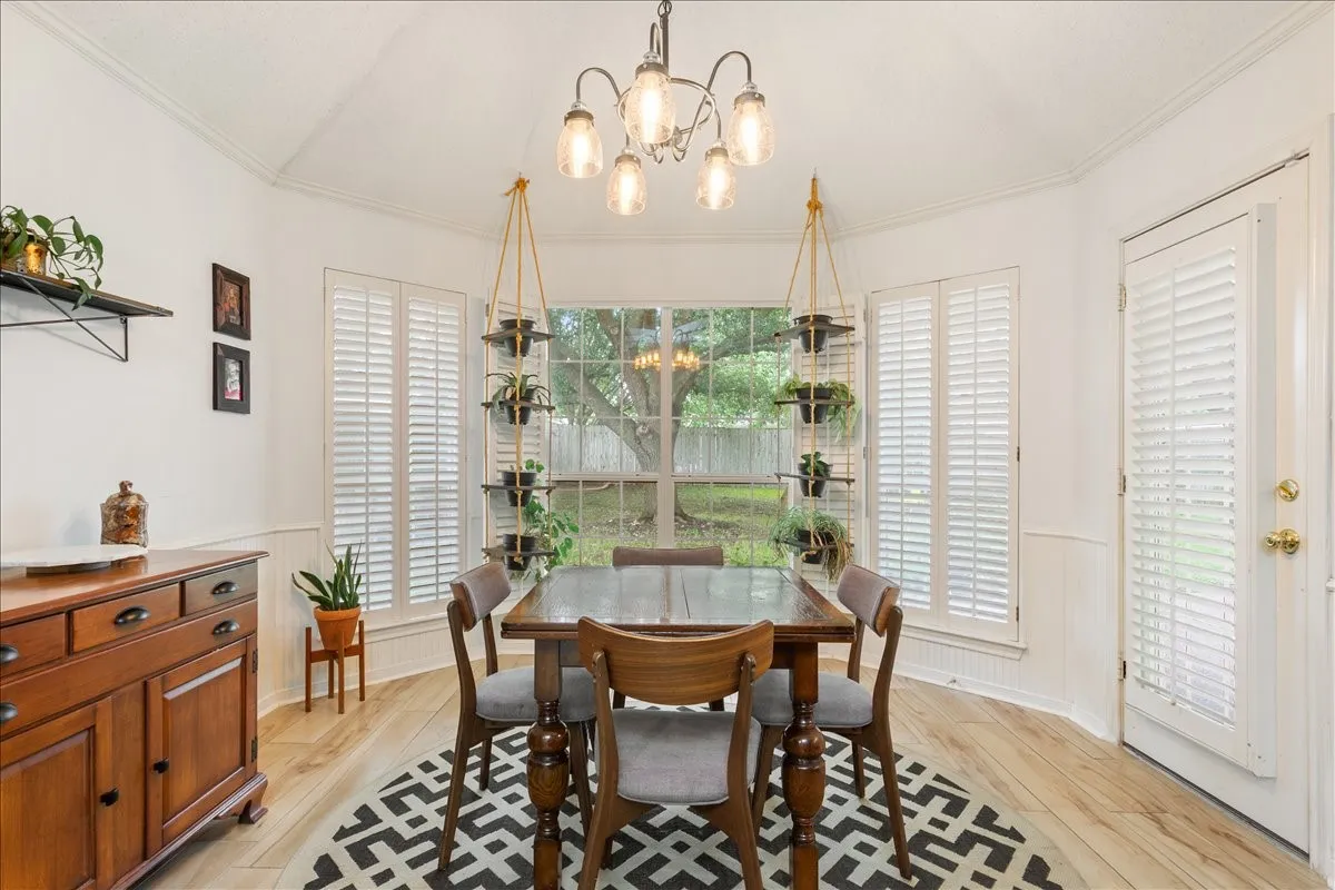 Tray ceiling with a five-light chandelier, wood-finish flooring, white paneling, and an exterior door with louvered blinds
