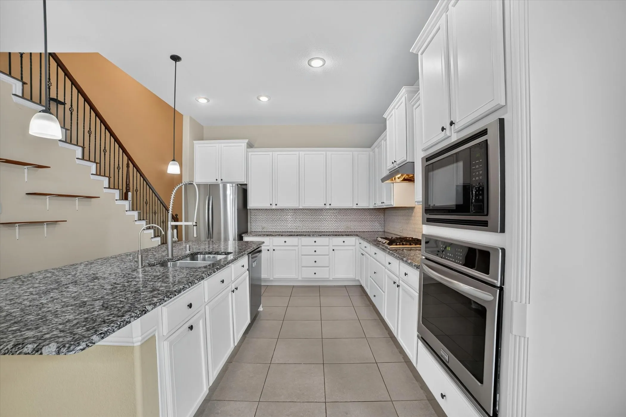 Bright kitchen featuring white cabinetry, stainless steel appliances, speckled stone countertops, and tile flooring