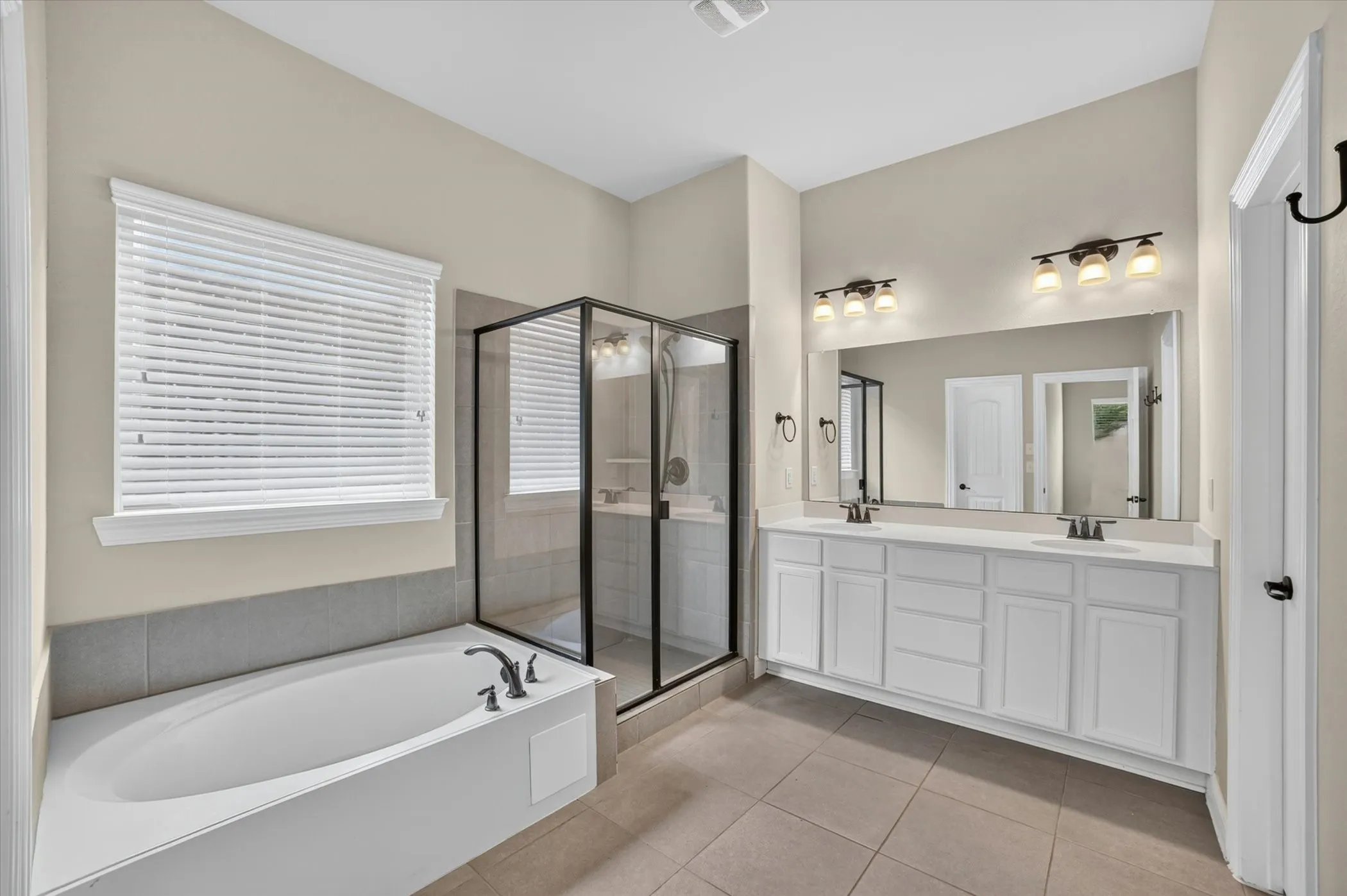 Bathroom featuring a dual-sink vanity with white cabinetry, light-toned countertops, and bronze-finish fixtures