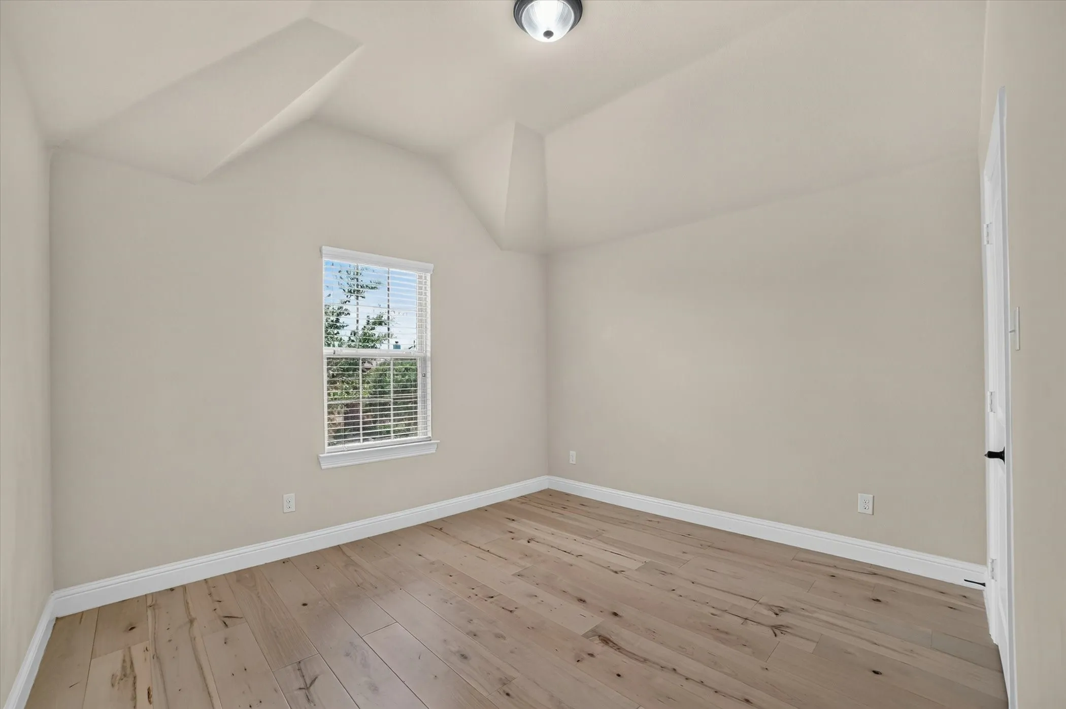 Bedroom featuring wood-finish flooring, neutral wall paint, and white baseboards