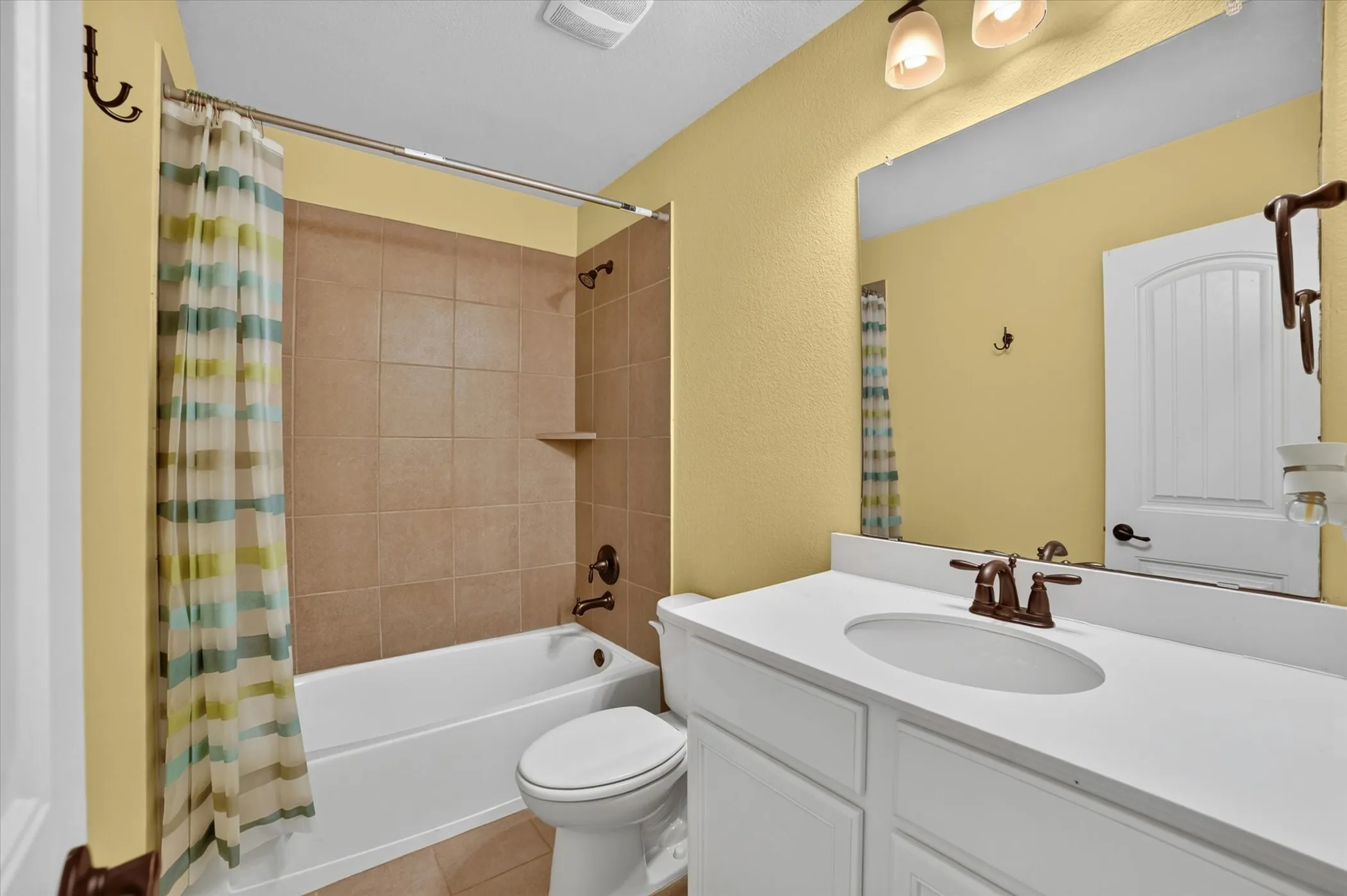 Bathroom vanity with a white countertop and integrated sink, complemented by a bronze-finish faucet