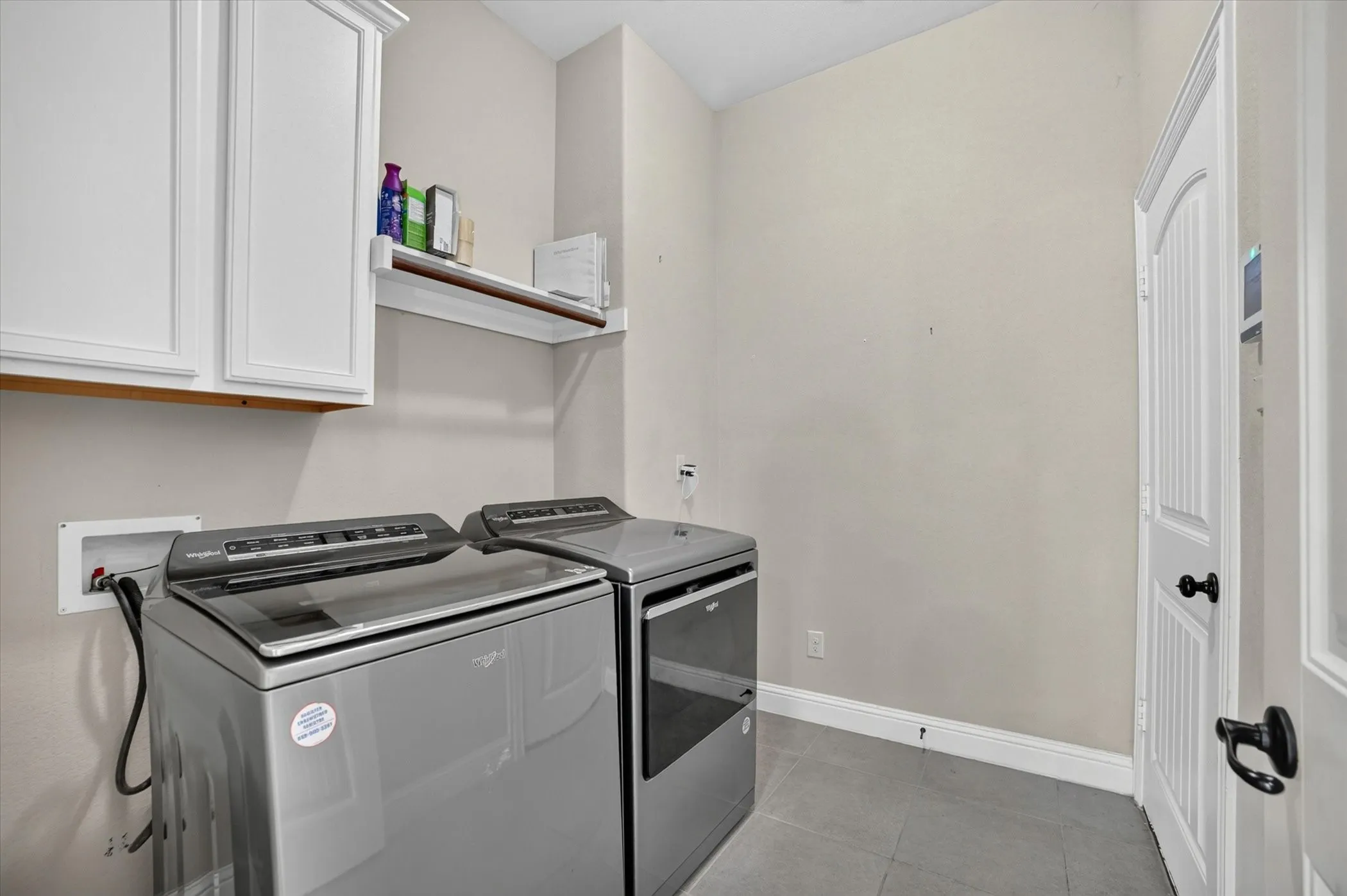 Laundry area featuring white cabinetry, a floating shelf, and neutral wall tones