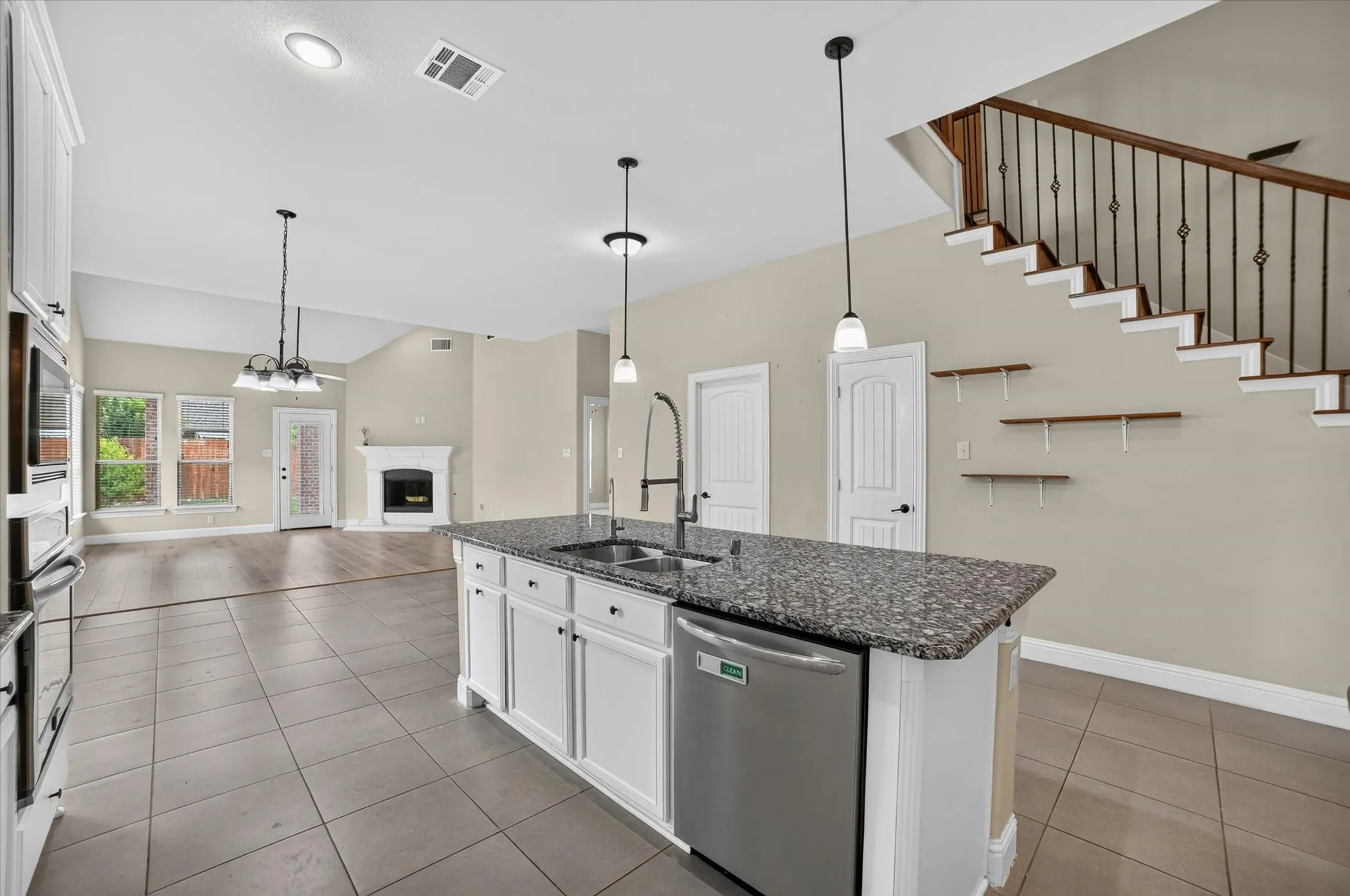 Kitchen island with granite countertop, double basin sink, and stainless steel dishwasher