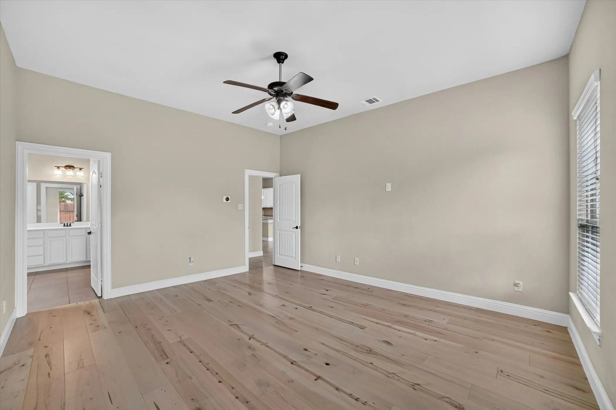 Spacious room featuring wood-finish flooring, vaulted ceilings, and a ceiling fan