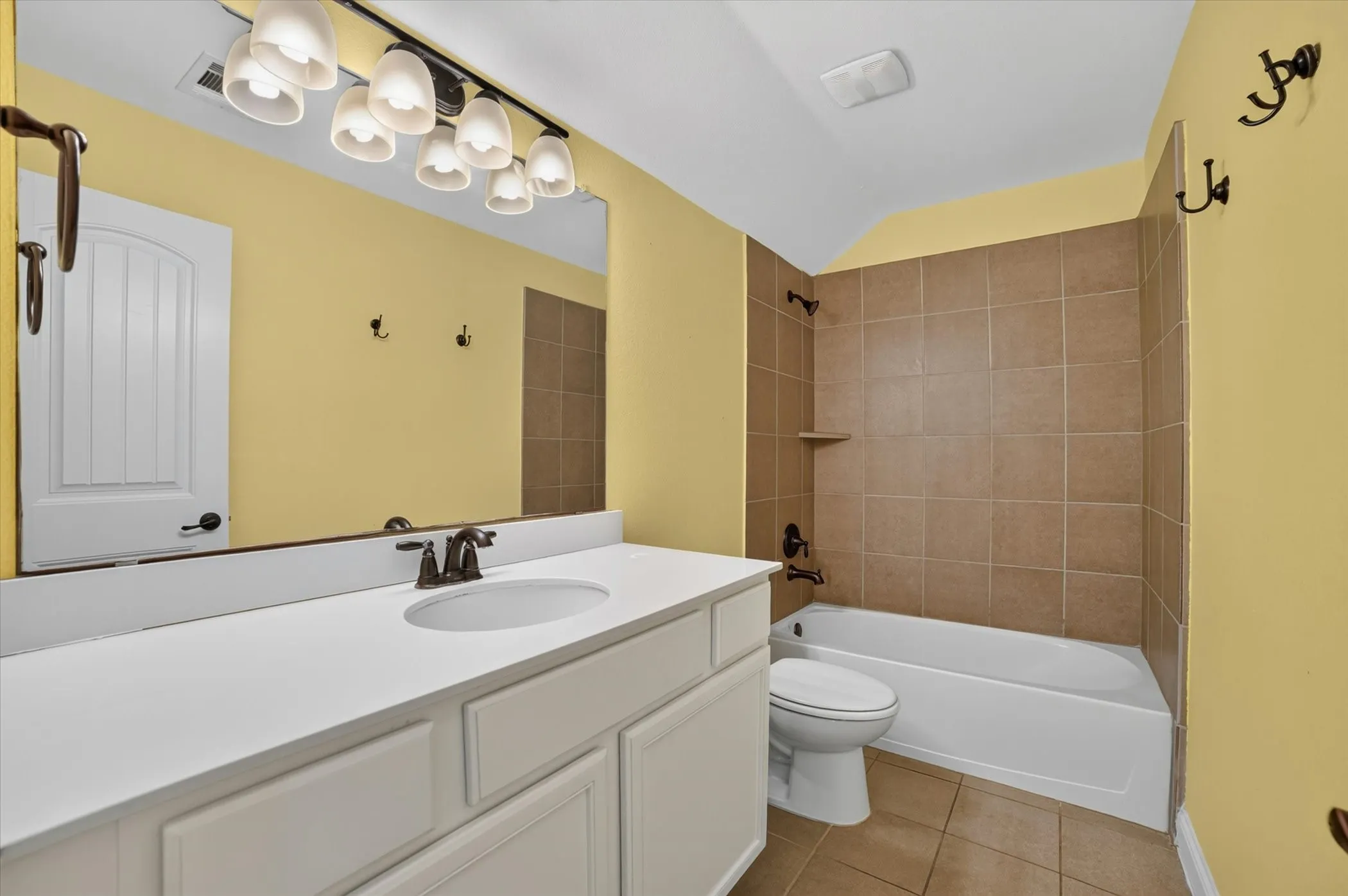 Bathroom featuring a white vanity with integrated sink, bronze-finish faucet, and a large wall-mounted mirror
