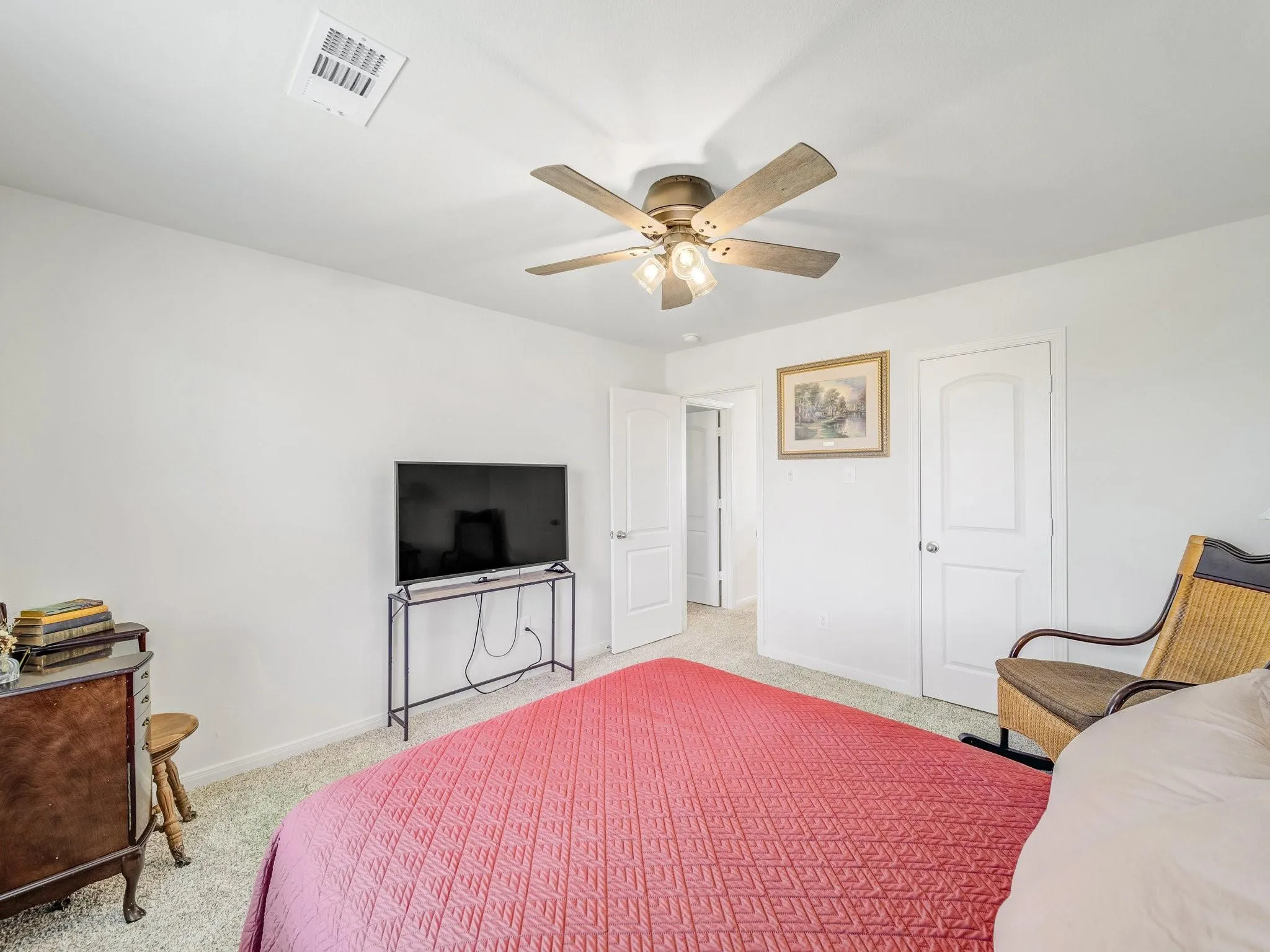 Carpeted room featuring a ceiling fan with integrated lighting, white walls, and a white interior door