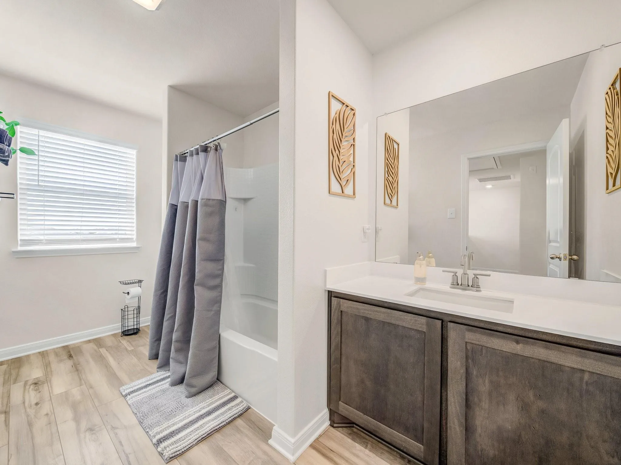 Bathroom with wood-finish flooring, a white vanity countertop, and a built-in sink