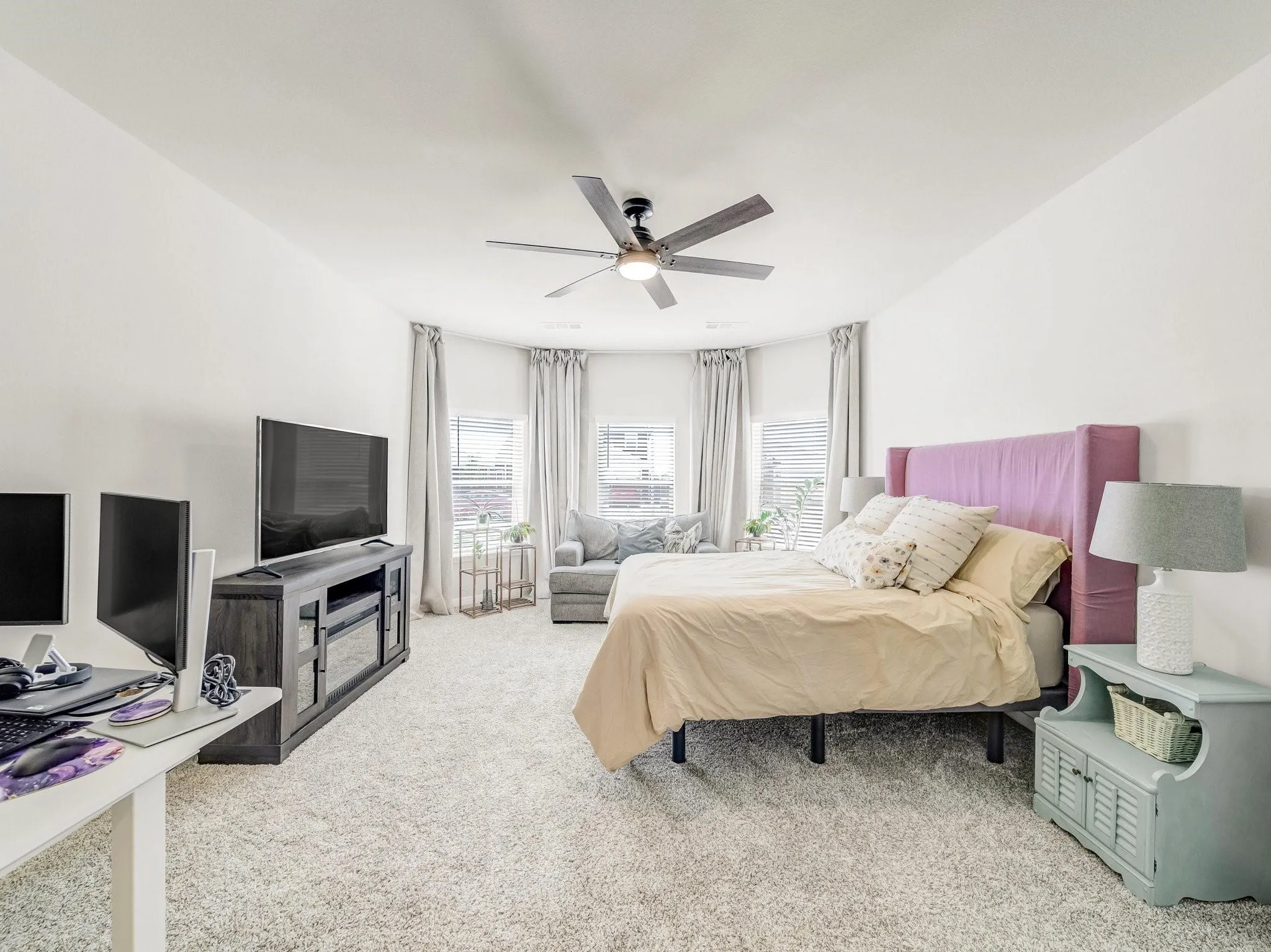 Carpeted room with a bay window feature and a ceiling fan with integrated lighting
