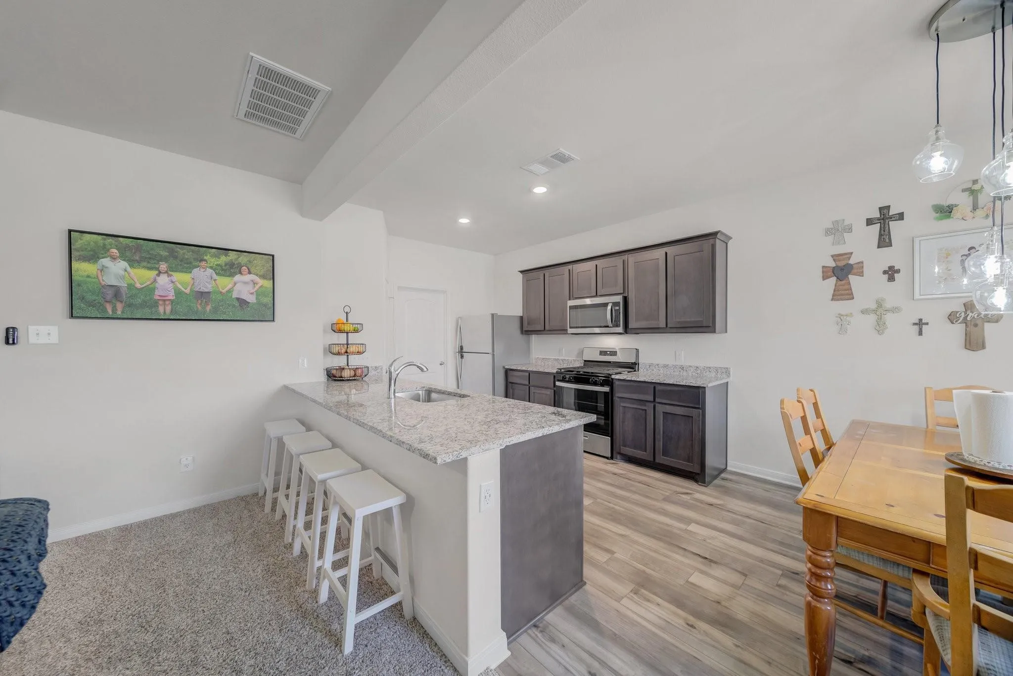 Kitchen featuring an island with granite countertop and undermount sink, dark wood cabinetry, stainless steel appliances, and wood-finish flooring