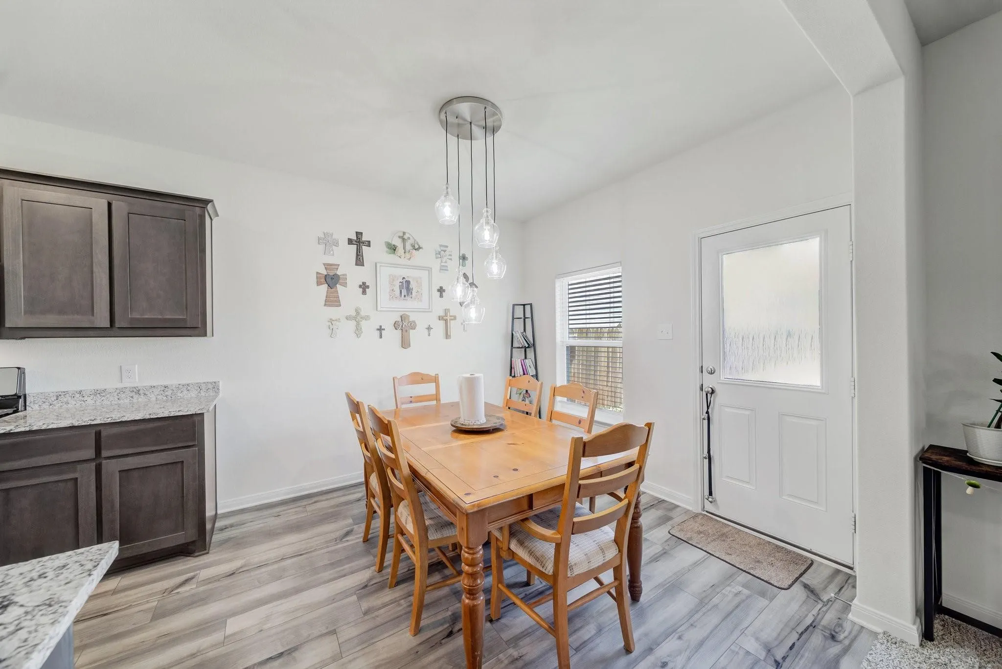 Dining area featuring wood-finish flooring and a contemporary multi-bulb pendant light fixture